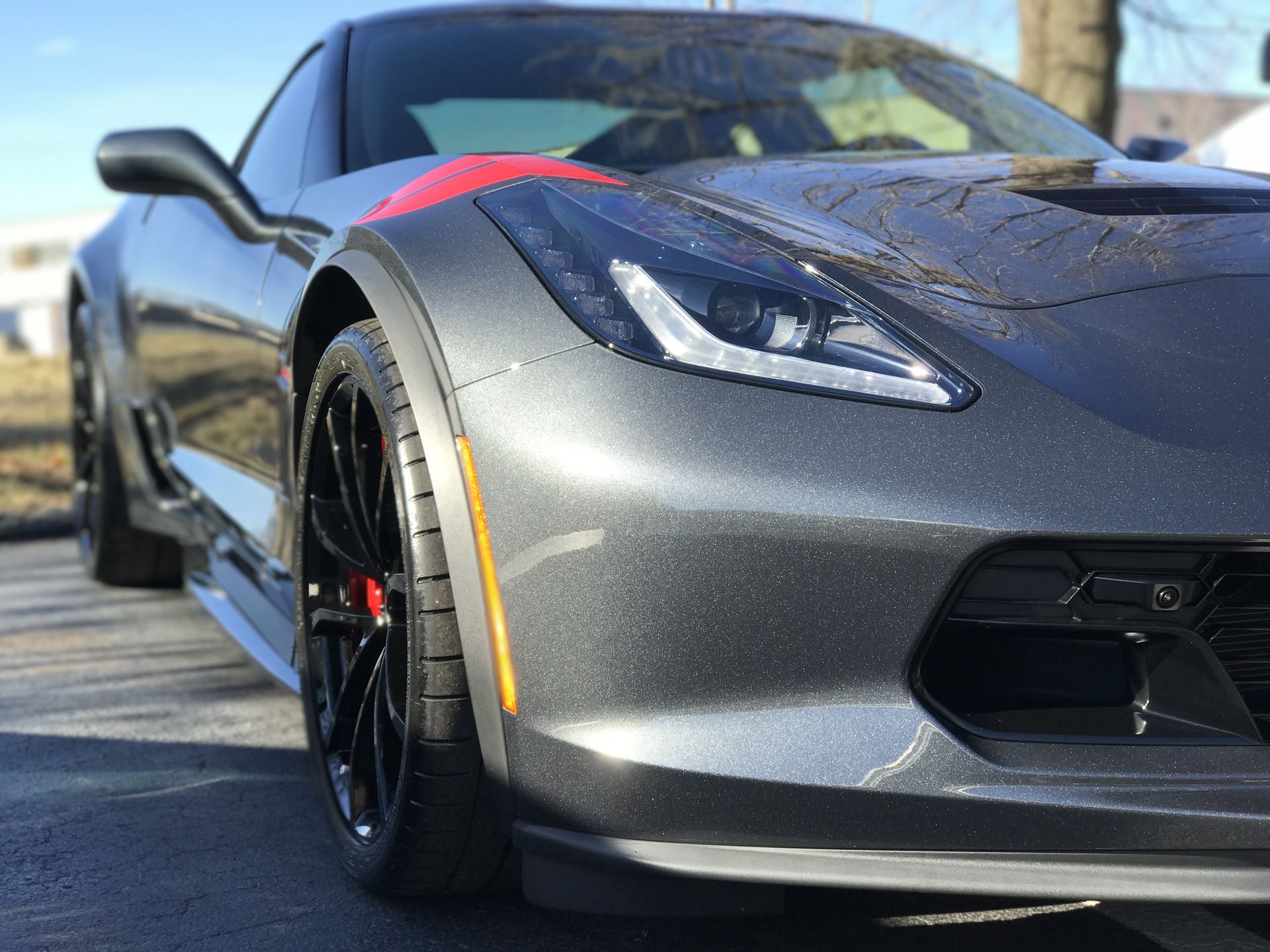 A black sports car with a red stripe on the side is parked in a driveway.