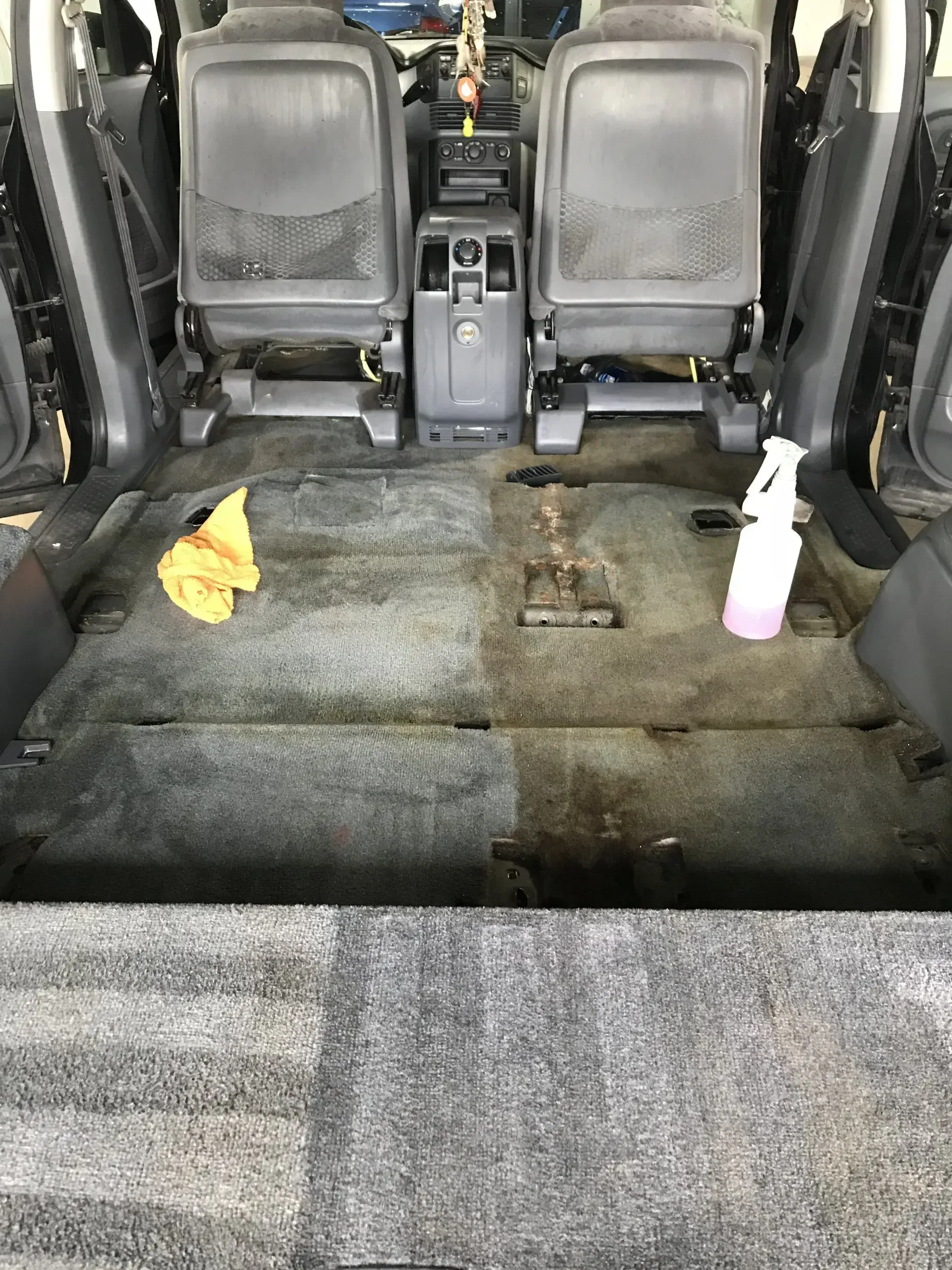 The back seat of a car is being cleaned with a spray bottle.