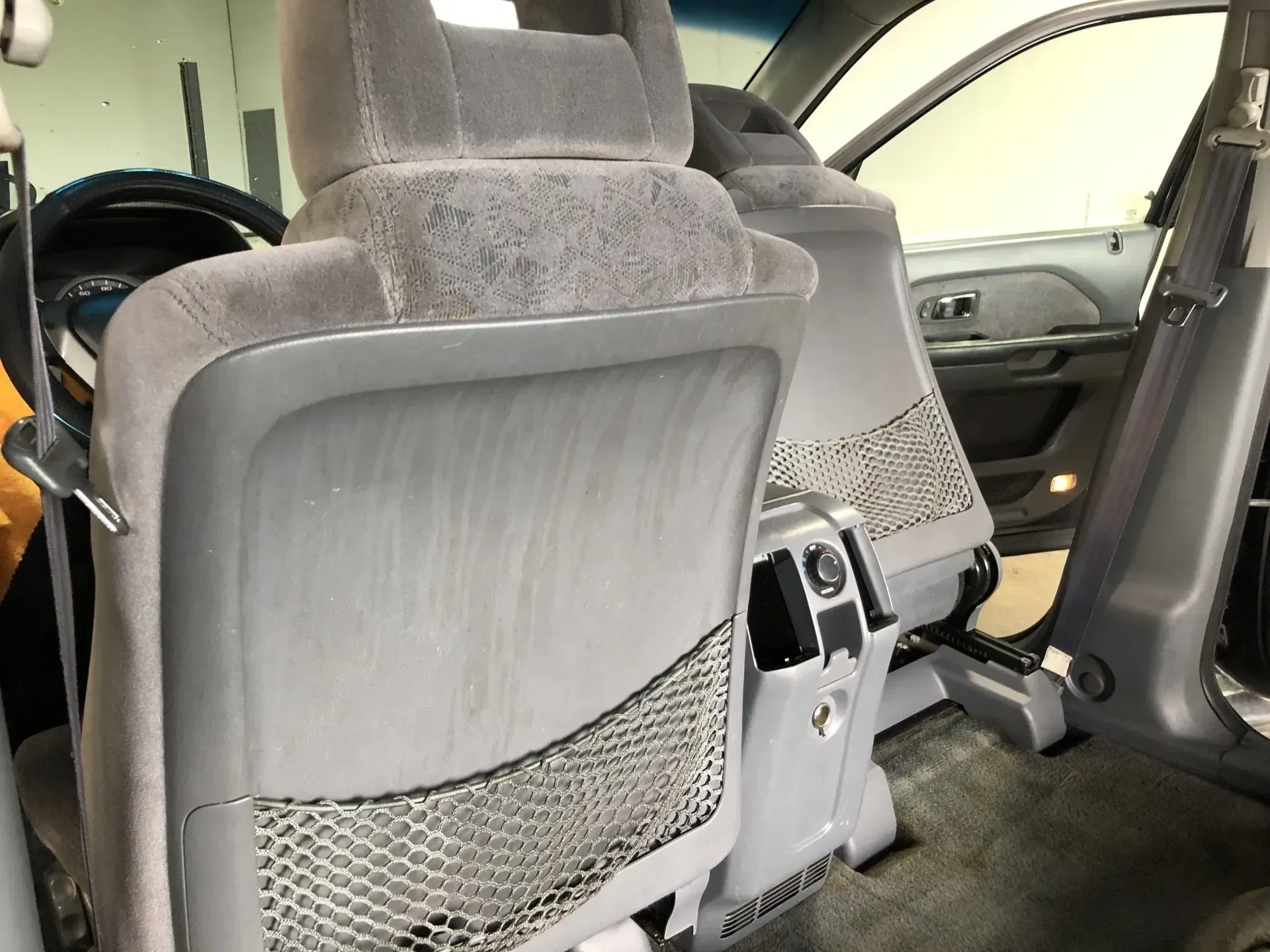 The back seat of a car with a mesh pocket between the seats.