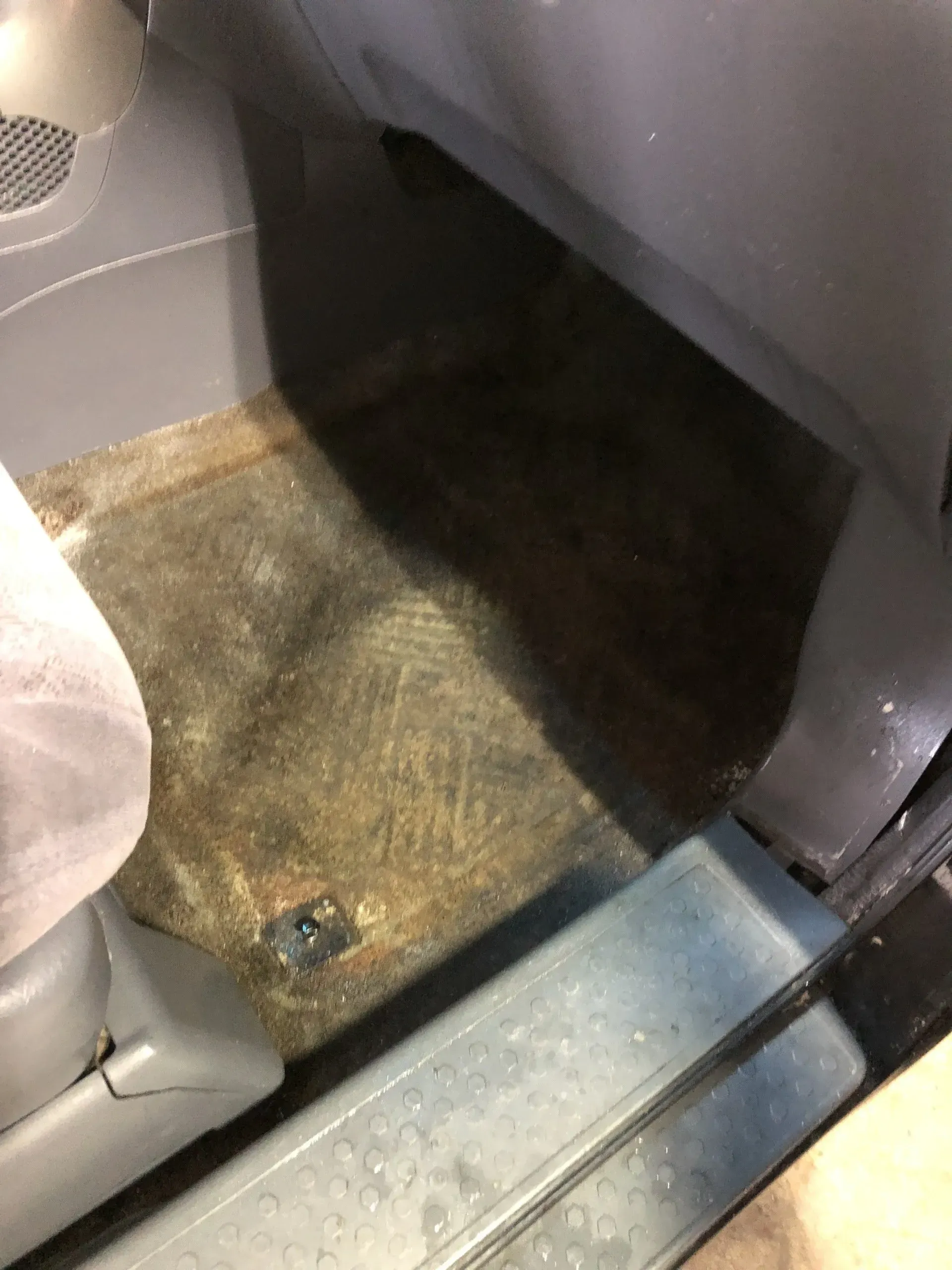 A close up of a dirty floor next to a toilet.
