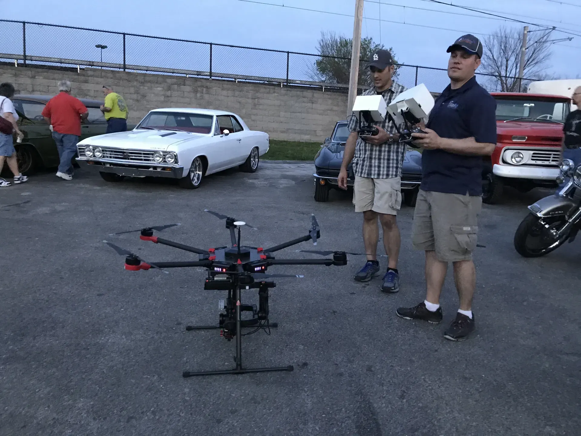 Two men are standing next to a drone in a parking lot