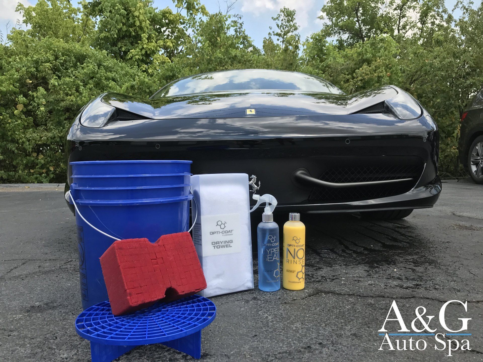 A black sports car is parked next to a bucket and sponge.