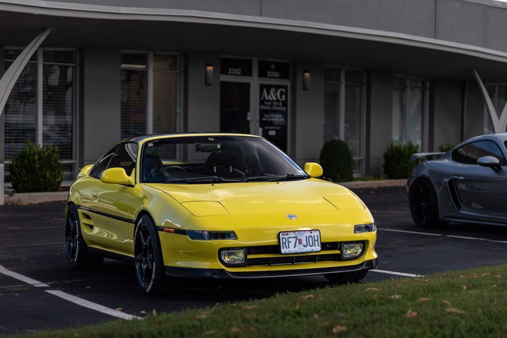 A yellow sports car is parked in front of a building.
