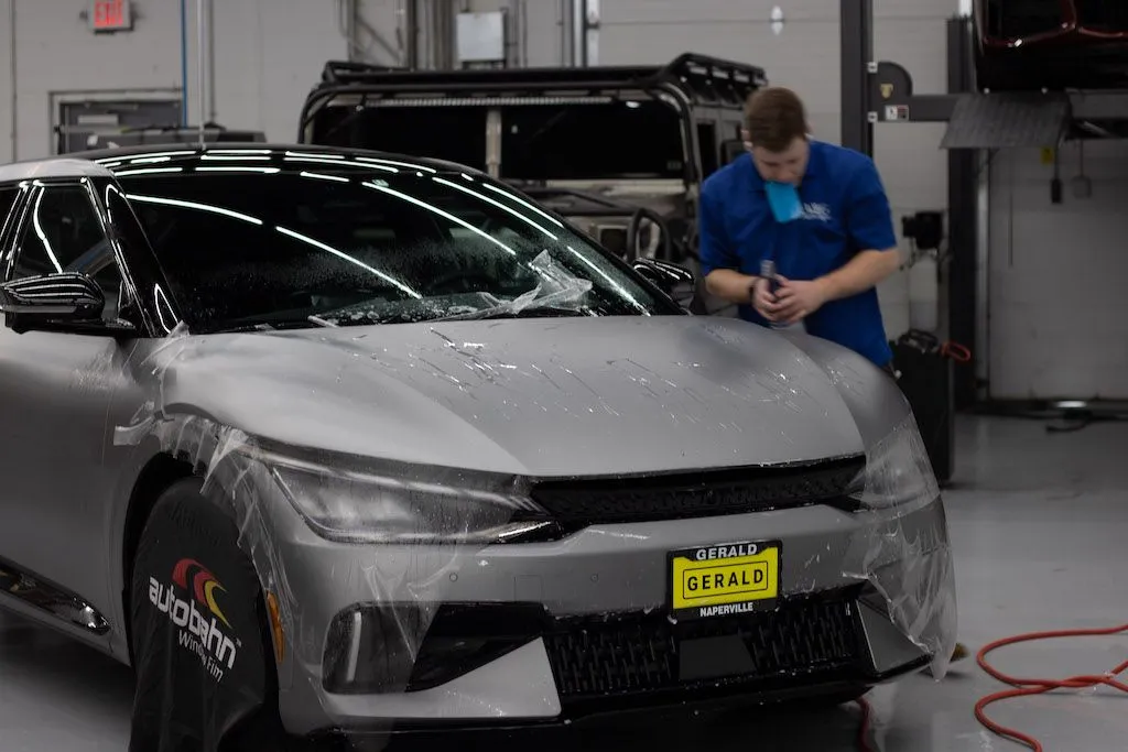 A person is applying protective film to the hood of a car.