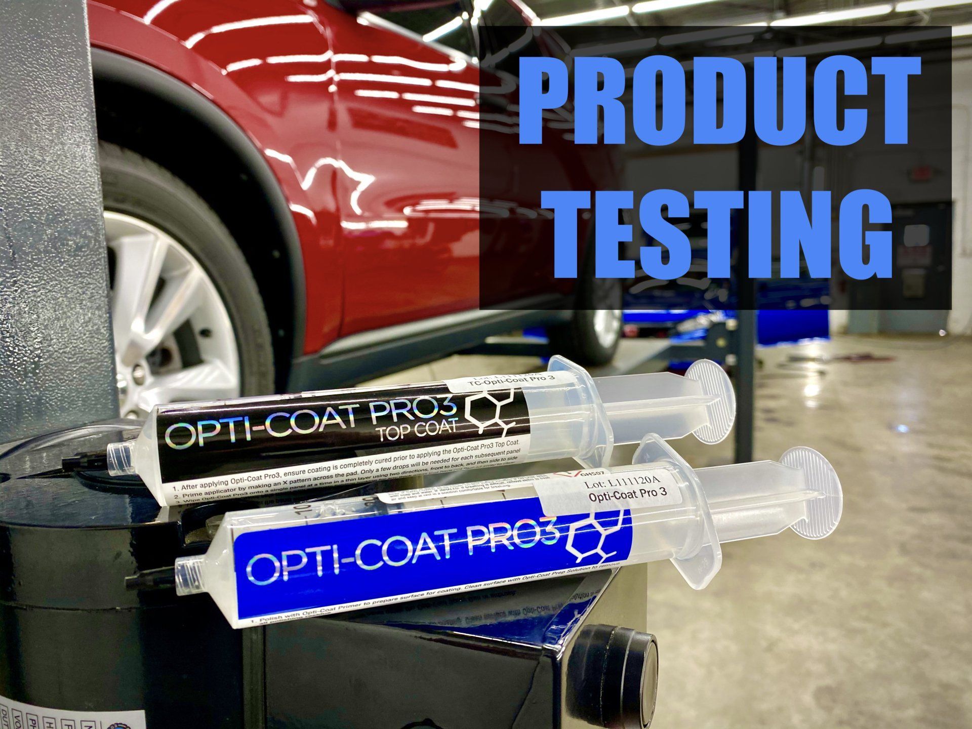 A red car is sitting in a garage next to a stack of syringes that say product testing
