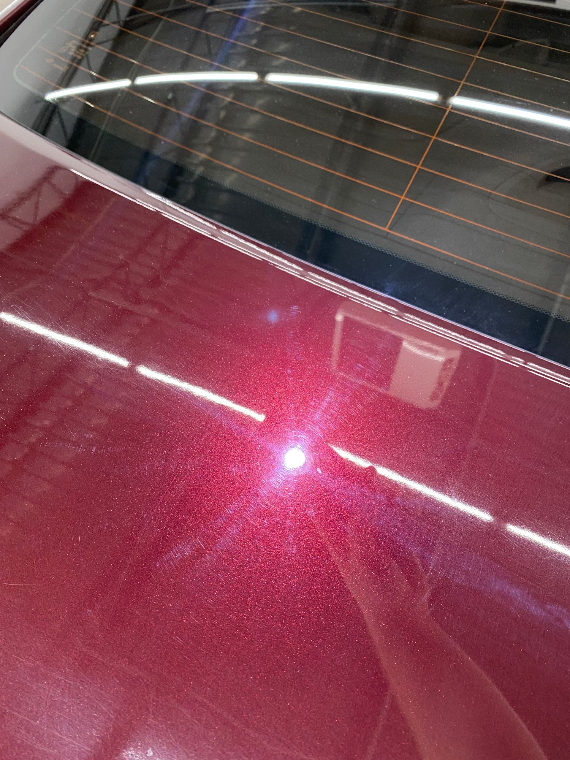 A close up of a red car 's hood and windshield.