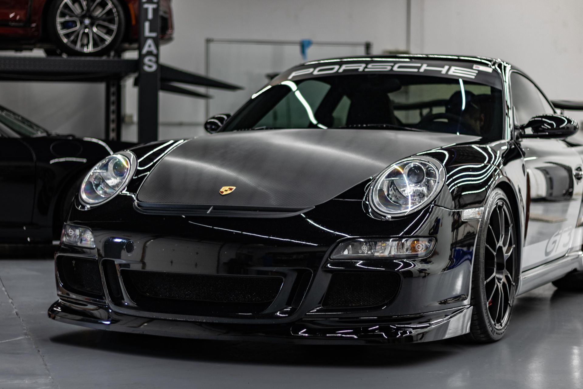 A black and white porsche 911 is parked in a garage.