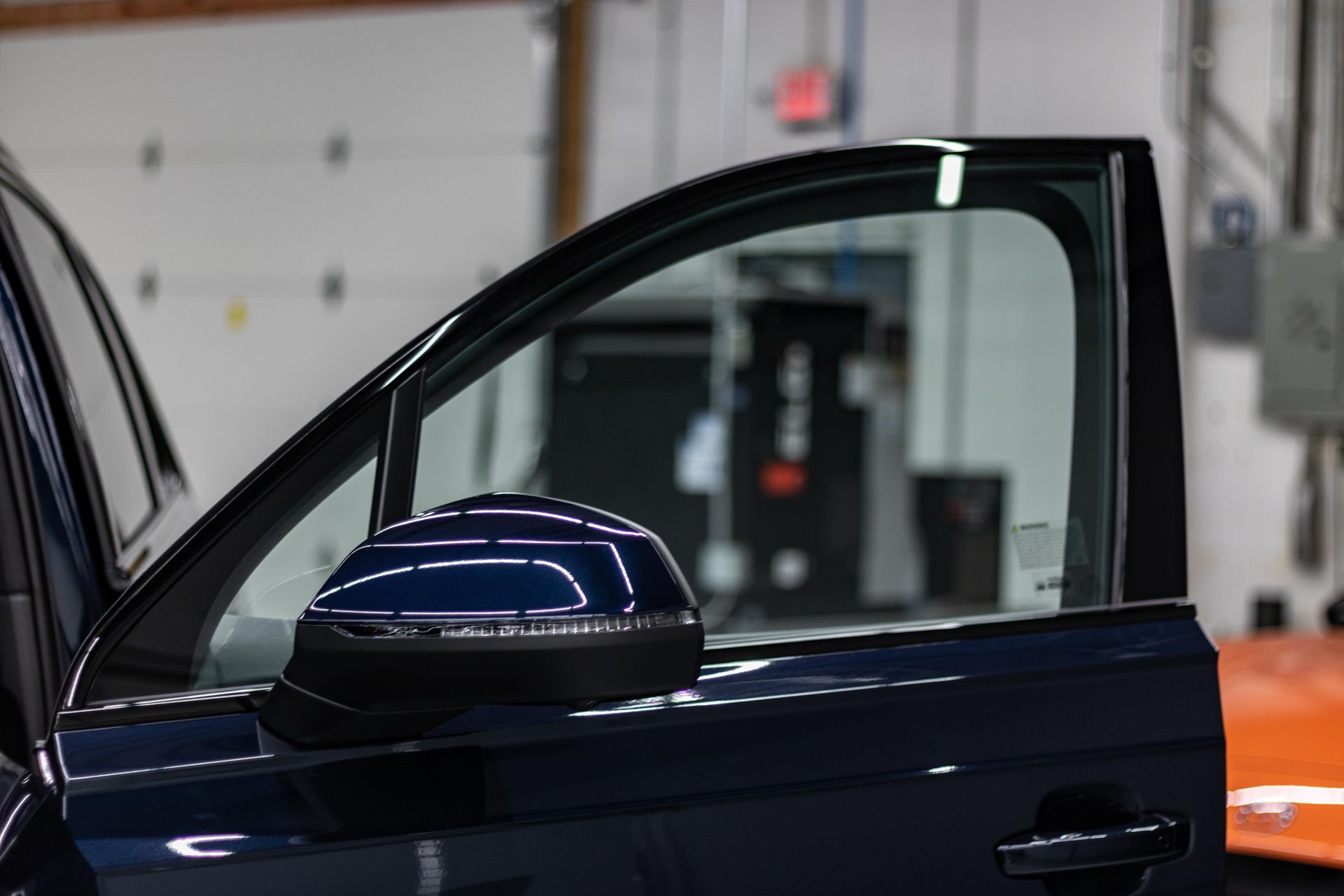 A blue car is parked in a garage with the door open.