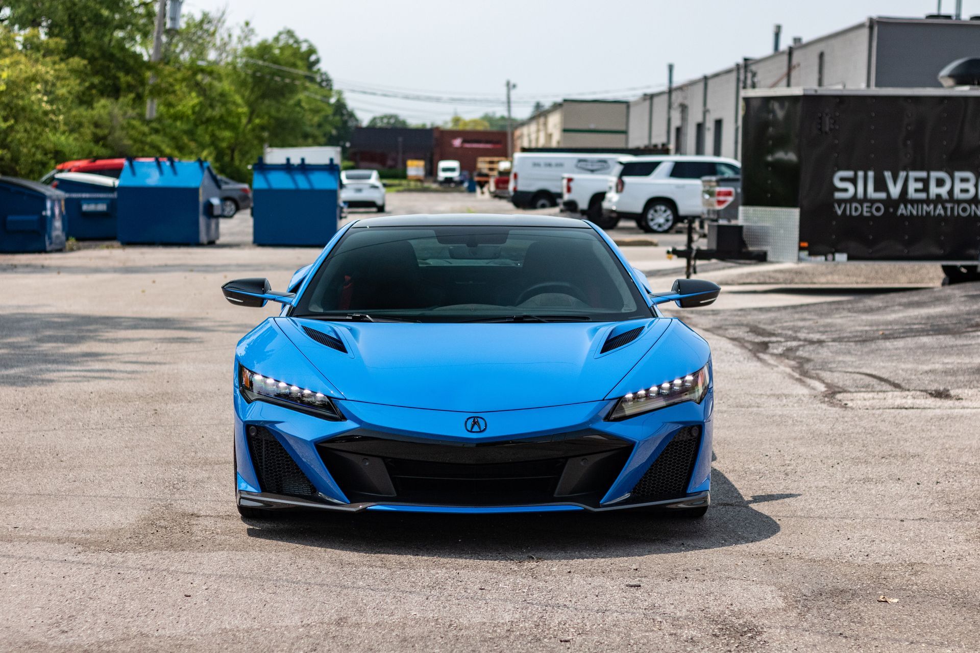 A blue sports car is parked in a parking lot in front of a building.