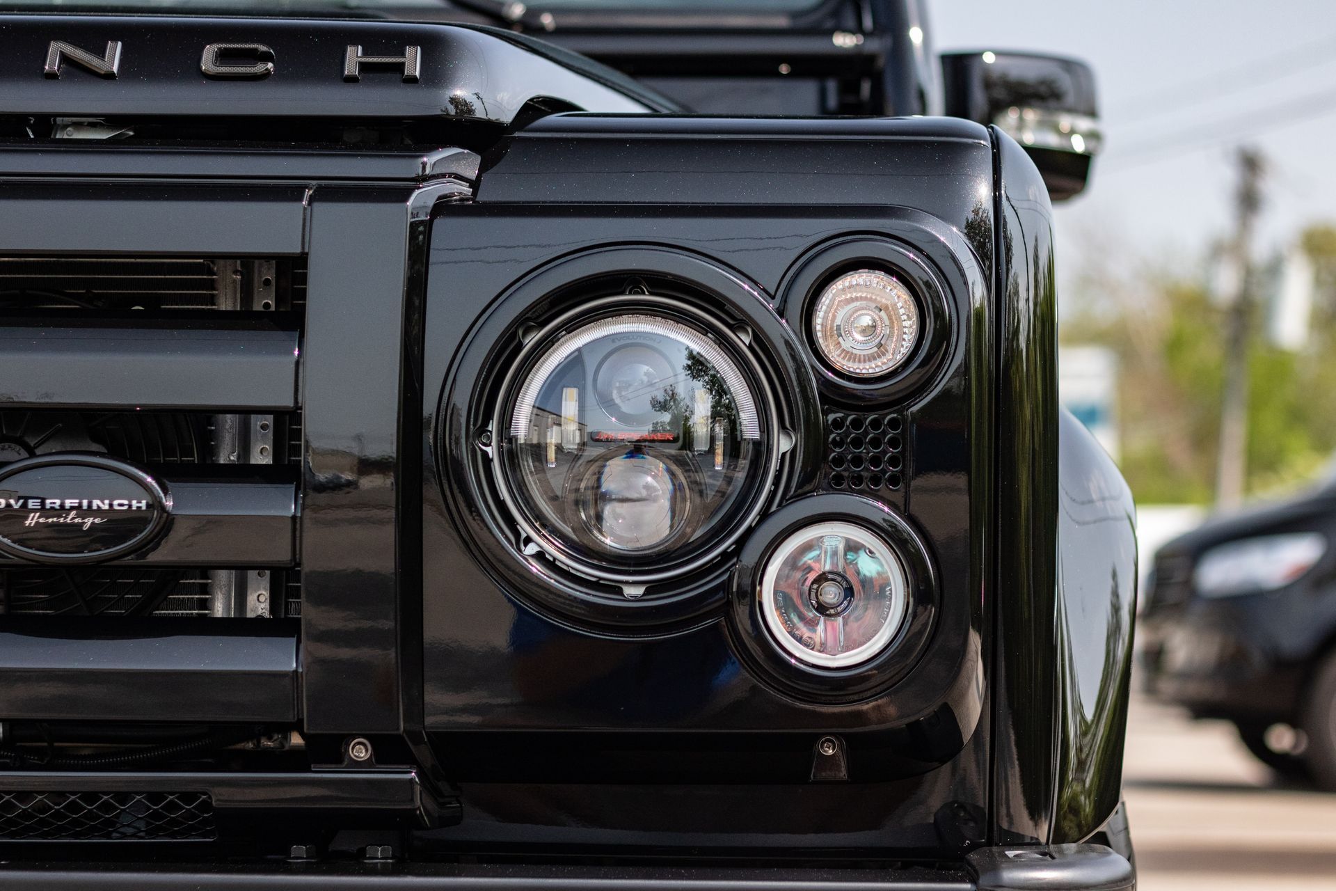 A close up of the front of a black land rover defender.