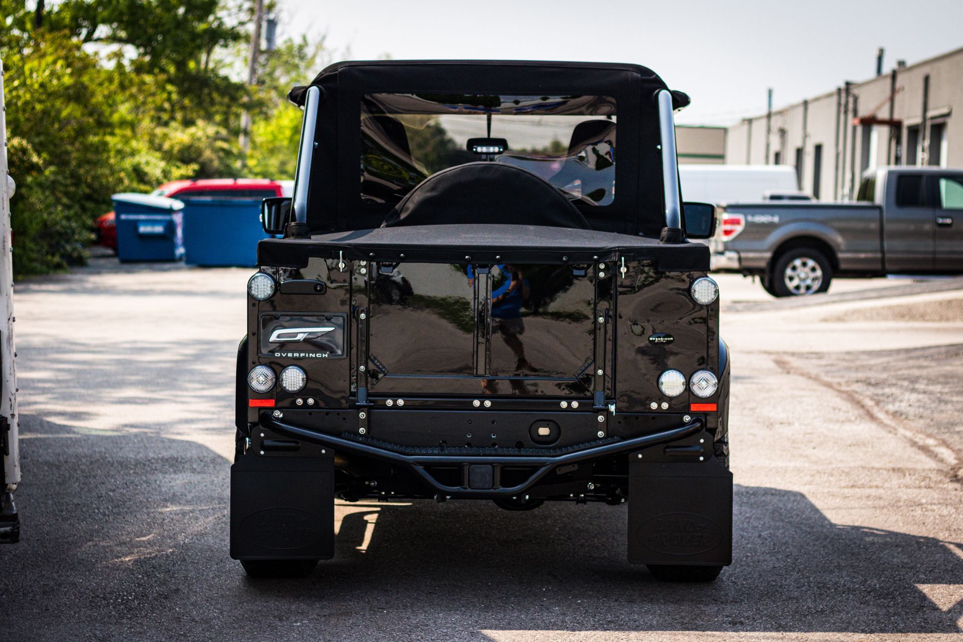 The back of a black jeep is parked in a parking lot.