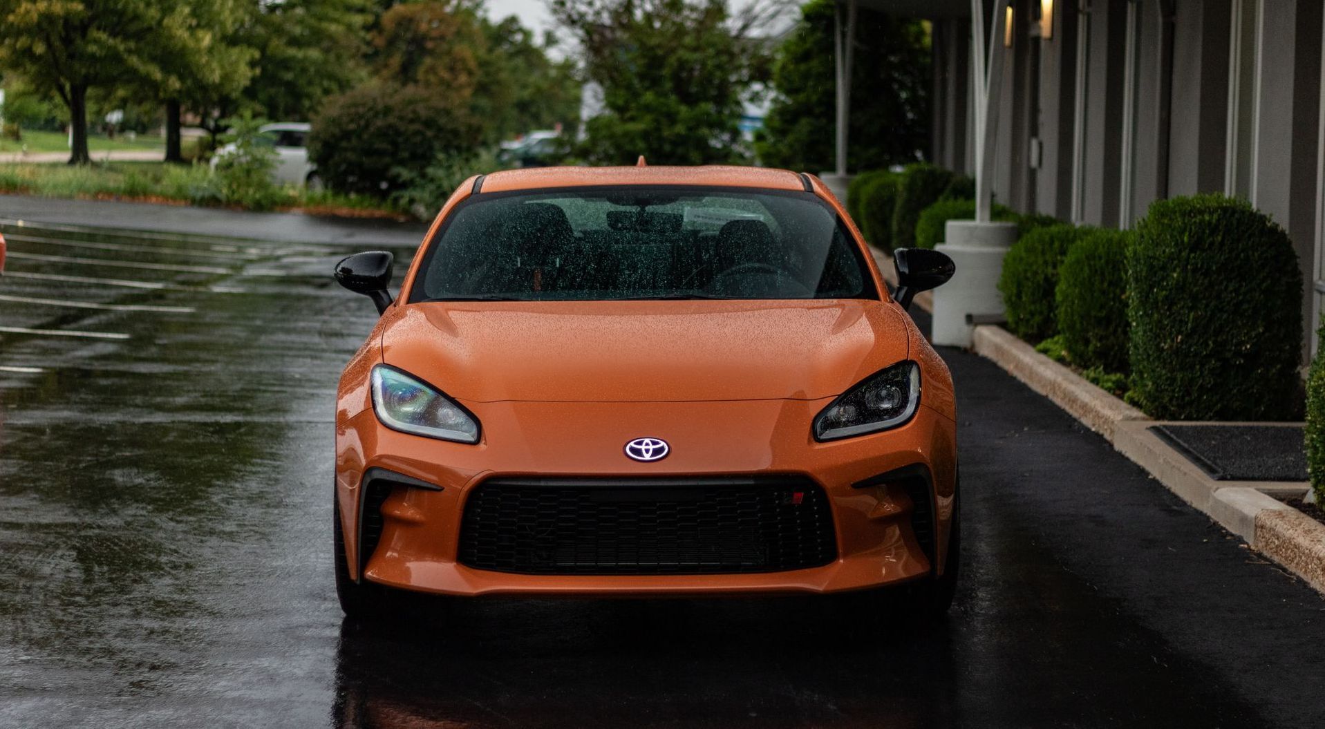 A toyota scion fr s is parked in a parking lot on a rainy day.
