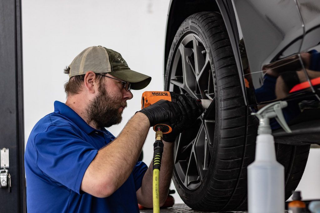 A man is working on a tire on a car in a garage.