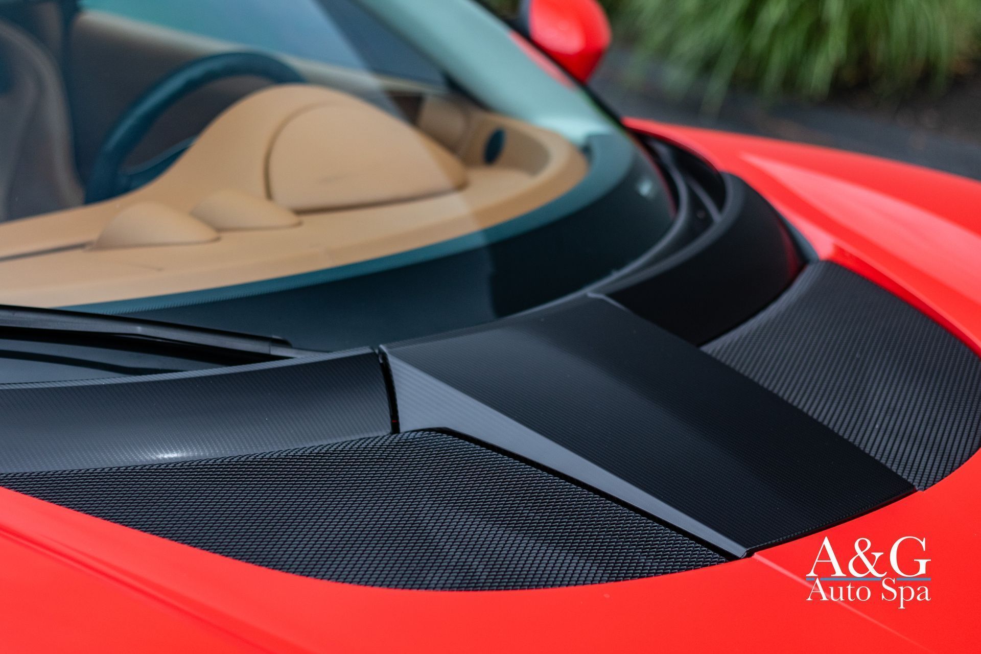 A close up of the hood of a red sports car sponsored by a & g auto spa
