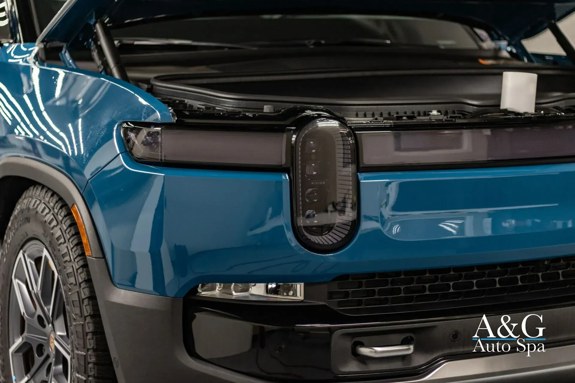 A close up of a blue car with the hood up.