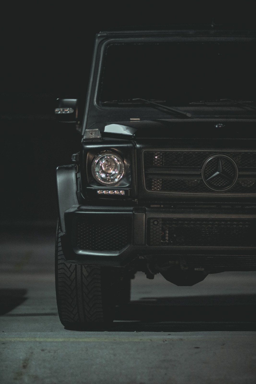 A black mercedes benz g63 amg is parked in a dark parking lot.