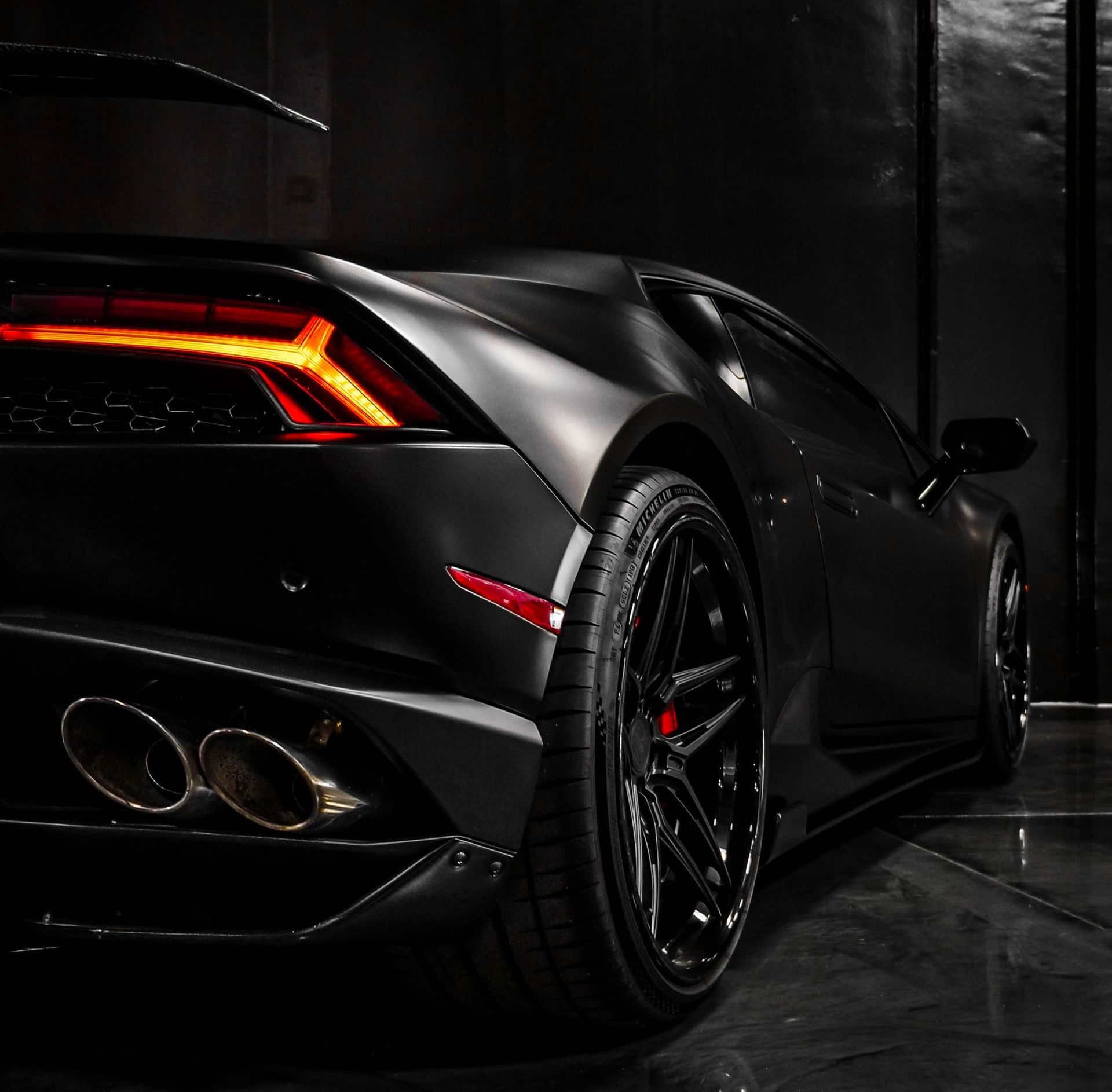 A black sports car is parked in a dark room