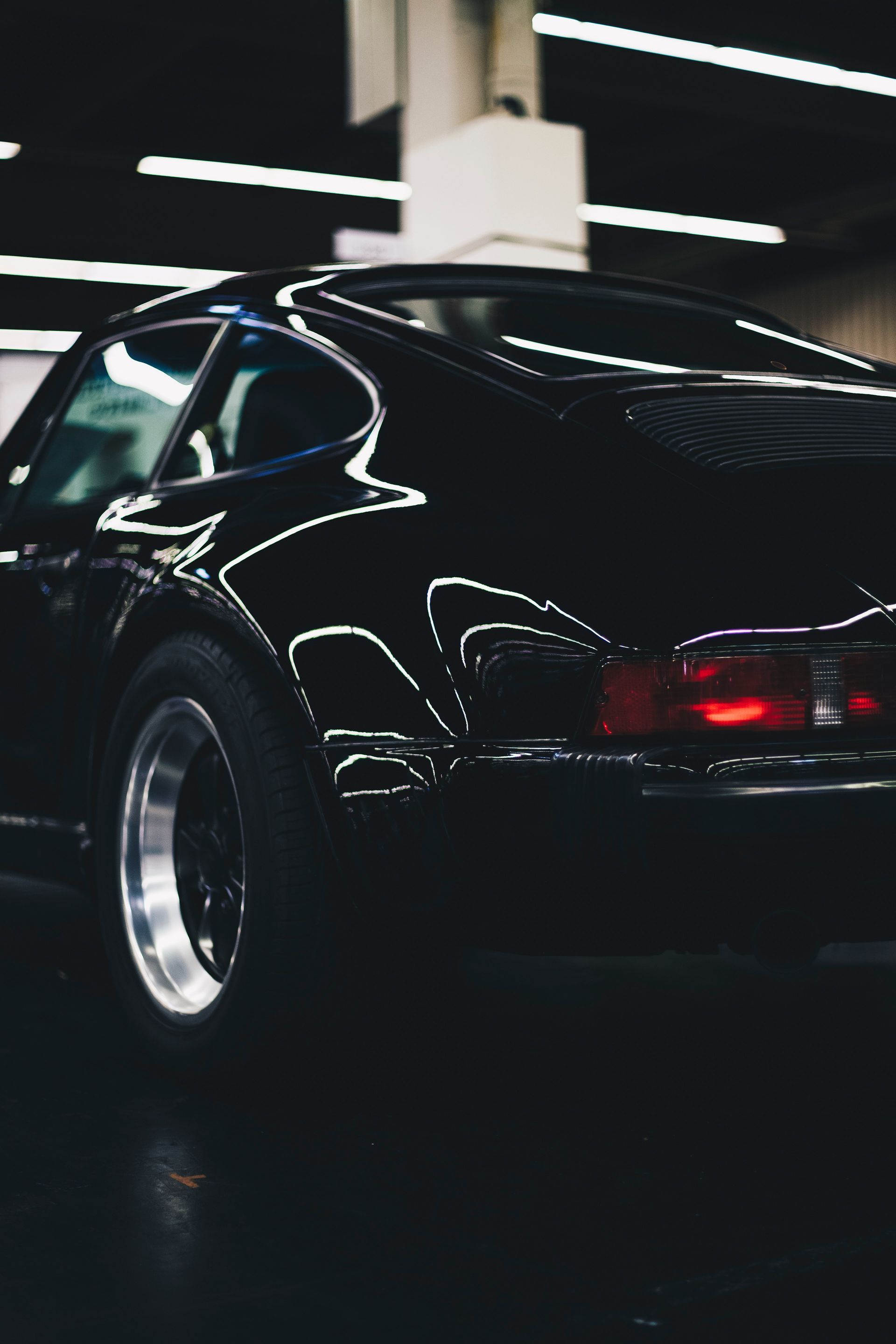 A black car is parked in a dark room
