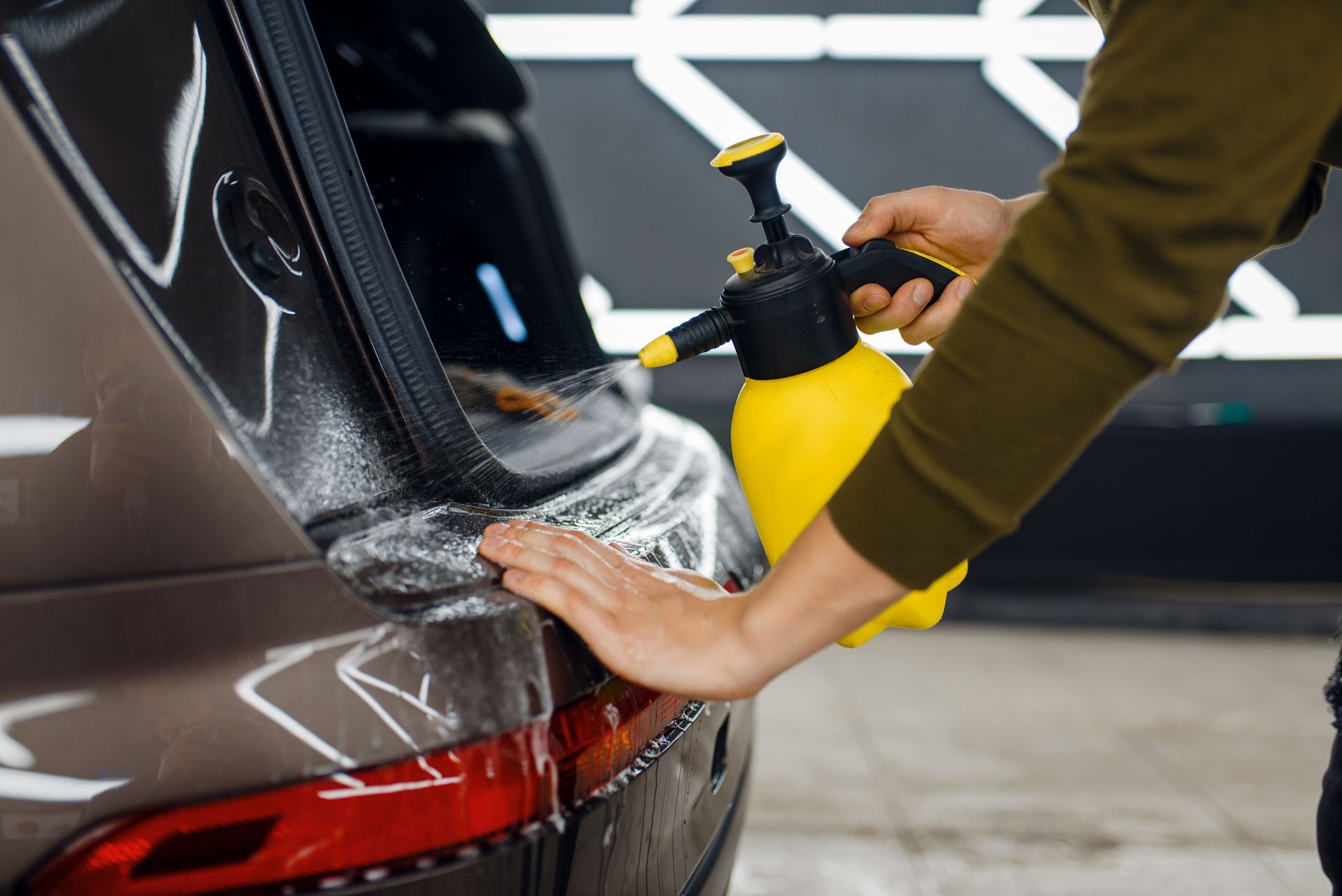 A person is spraying a car with a spray bottle.
