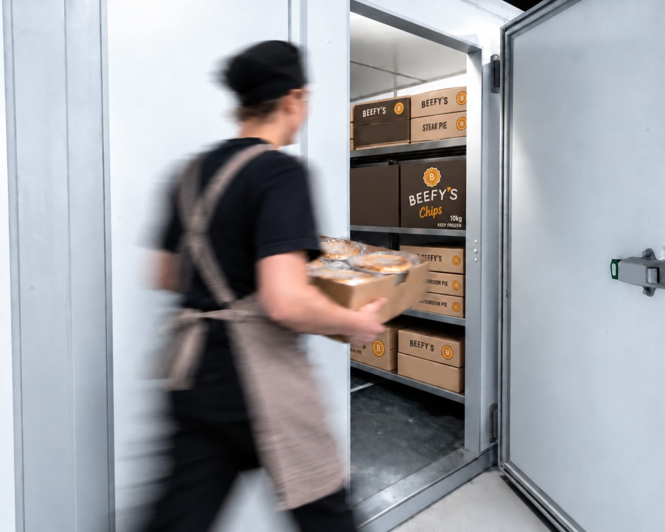 Person carrying boxes into a walk-in cooler stocked with boxes of groceries
