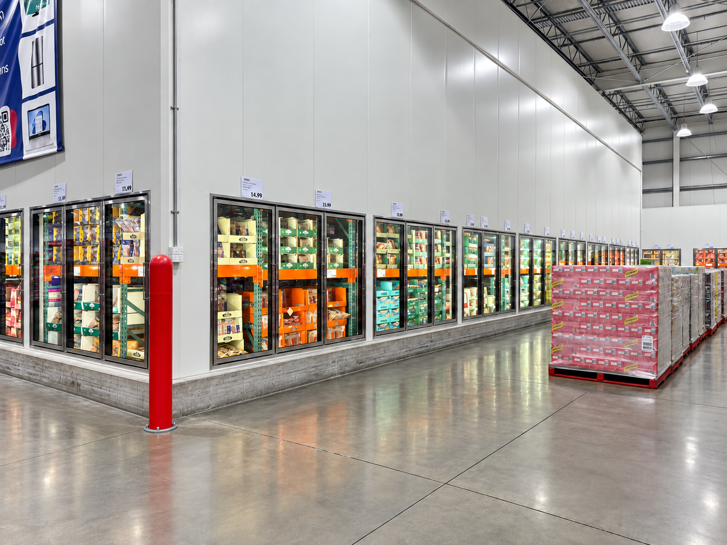 Grocery store freezer aisle with glass-doored refrigerated cases and a pink pallet display on a polished floor