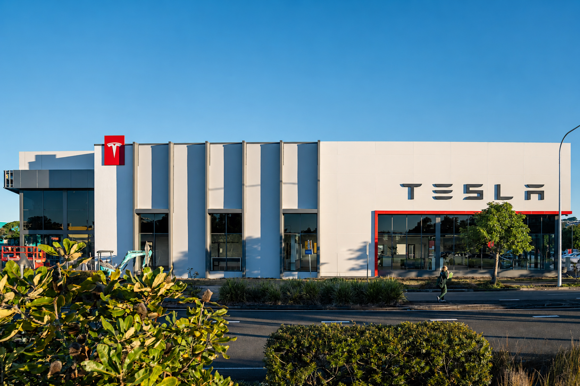Tesla dealership building with white facade, red Tesla logo, and blue sky overhead