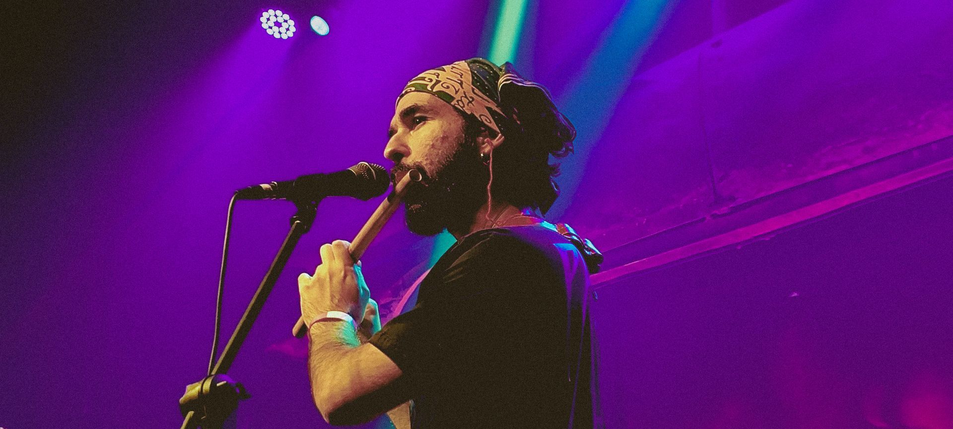 Pedro Francisco from Papangu is playing a flute and singing into a microphone on a stage.
