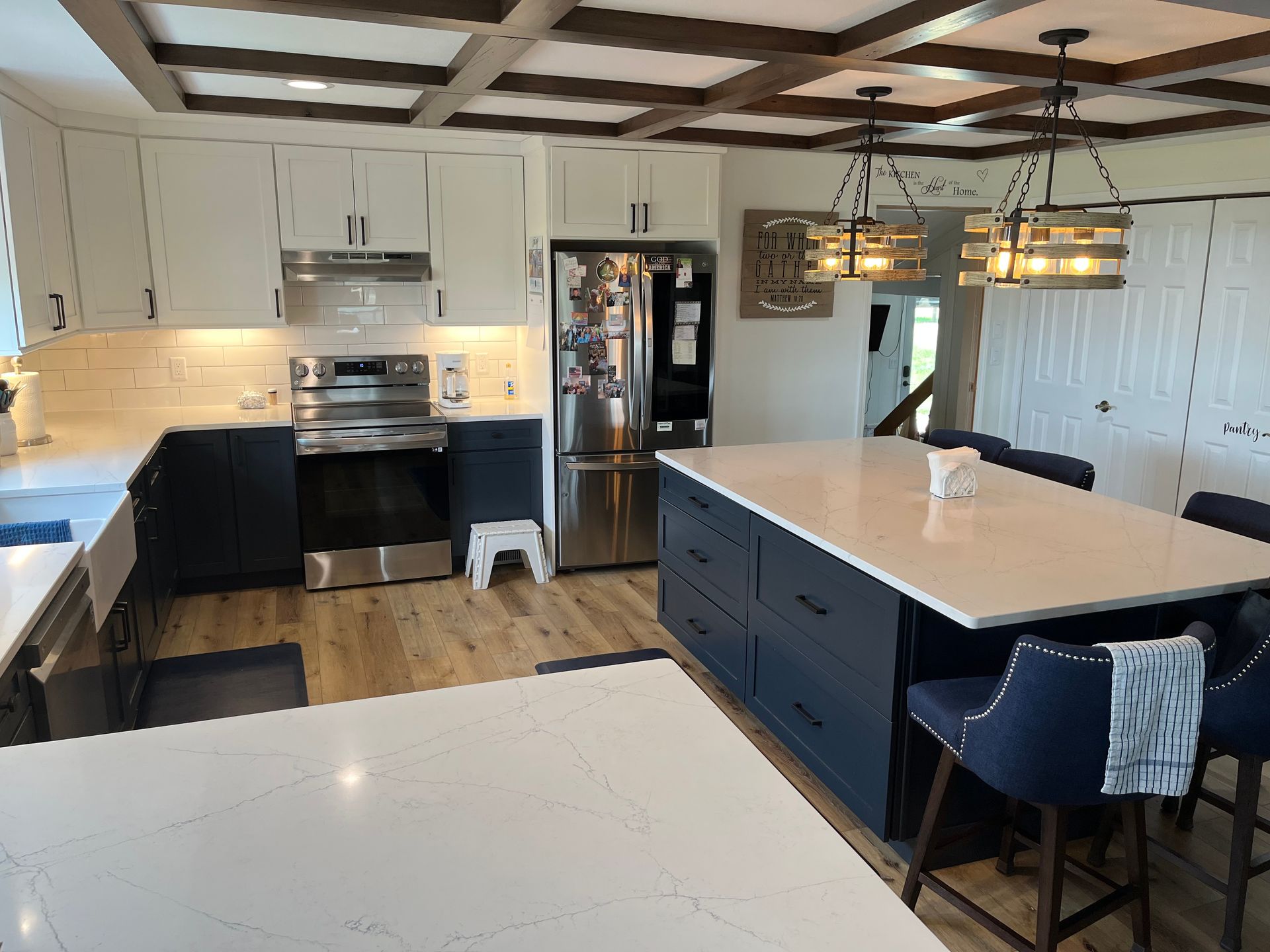 Modern kitchen with white cabinets, black island, stainless appliances, and pendant lights over the island