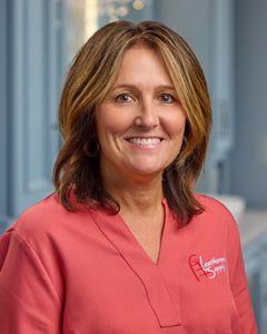 Smiling healthcare professional in a coral top against a blurred office background