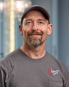 Man in a gray cap and shirt smiling against a softly blurred indoor background