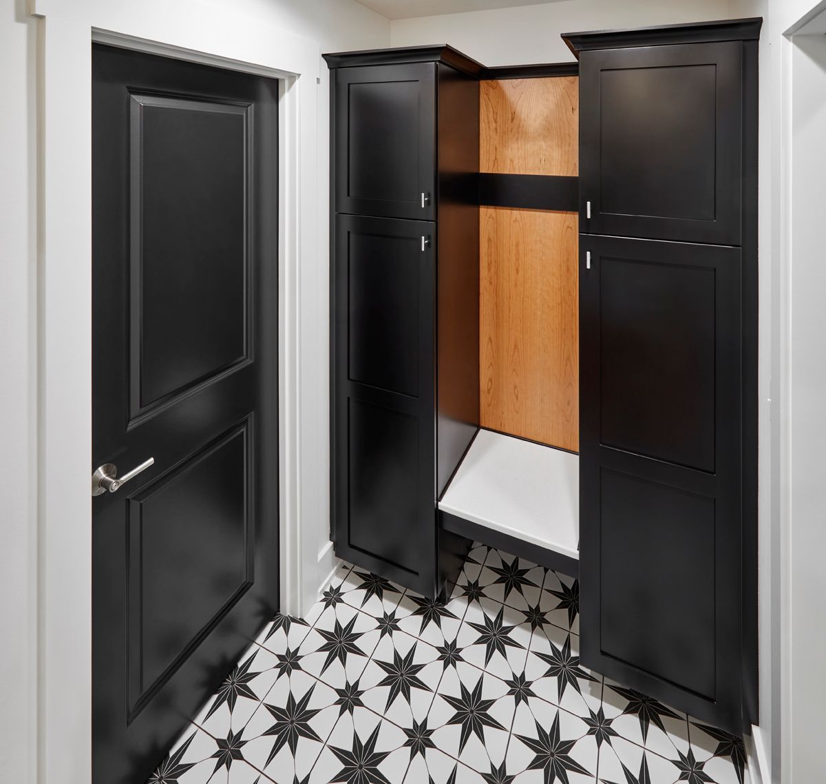 Black bathroom vanity cabinet open in a small tiled room with patterned black-and-white floor.