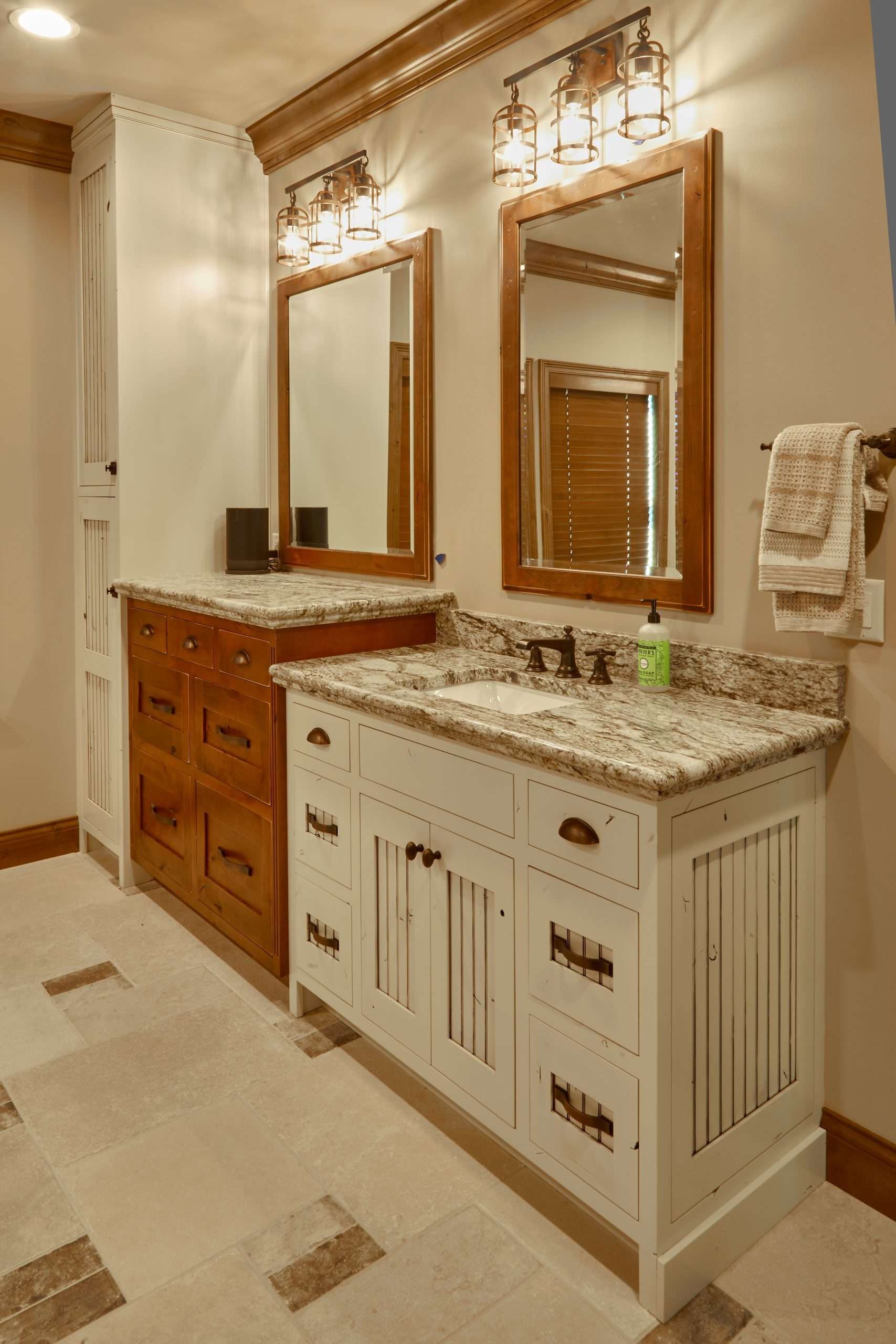Elegant bathroom with dual mirrors, wood vanity, marble countertop, and beige tile floor