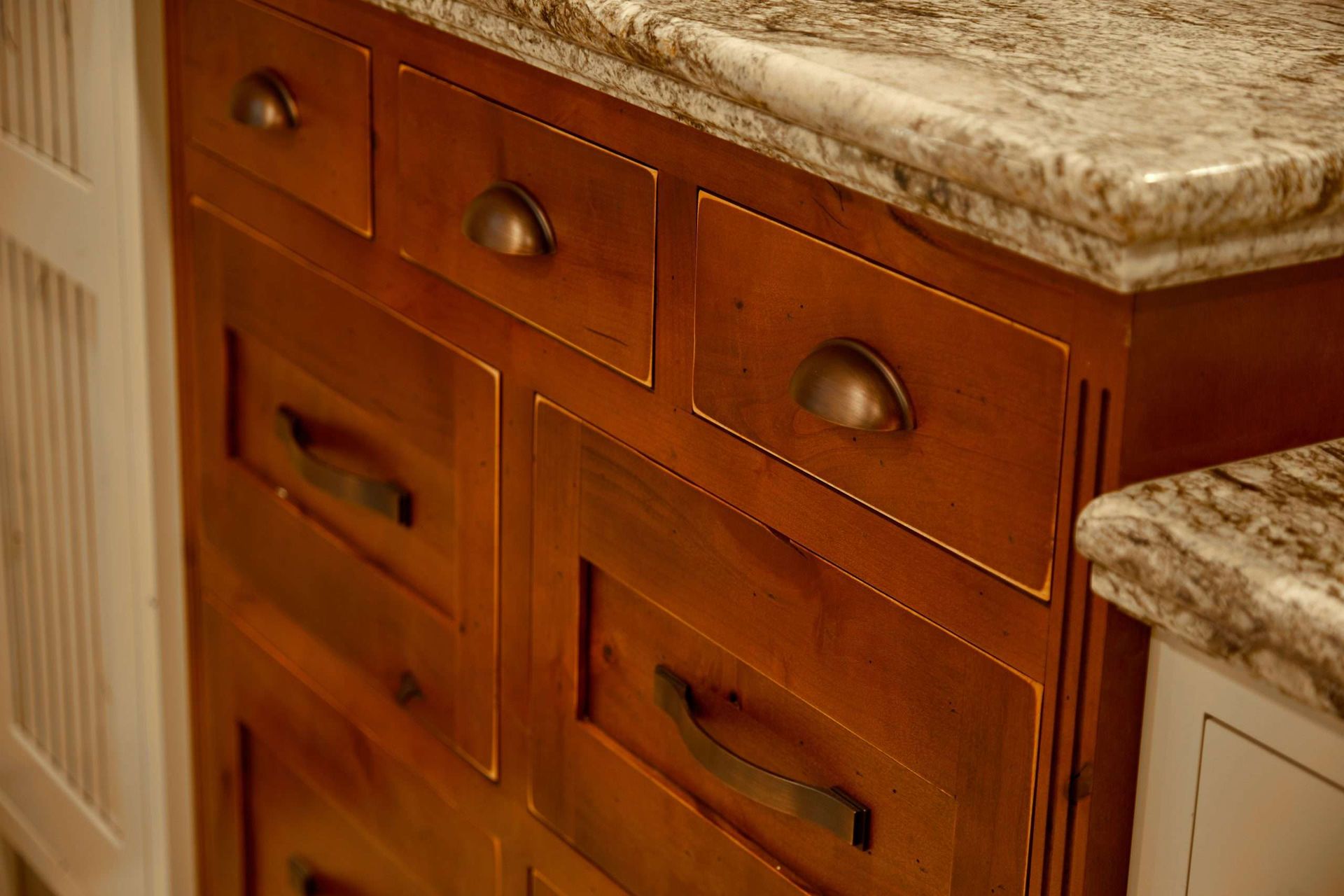 Wooden bathroom vanity with drawers and a marble countertop beside a white cabinet