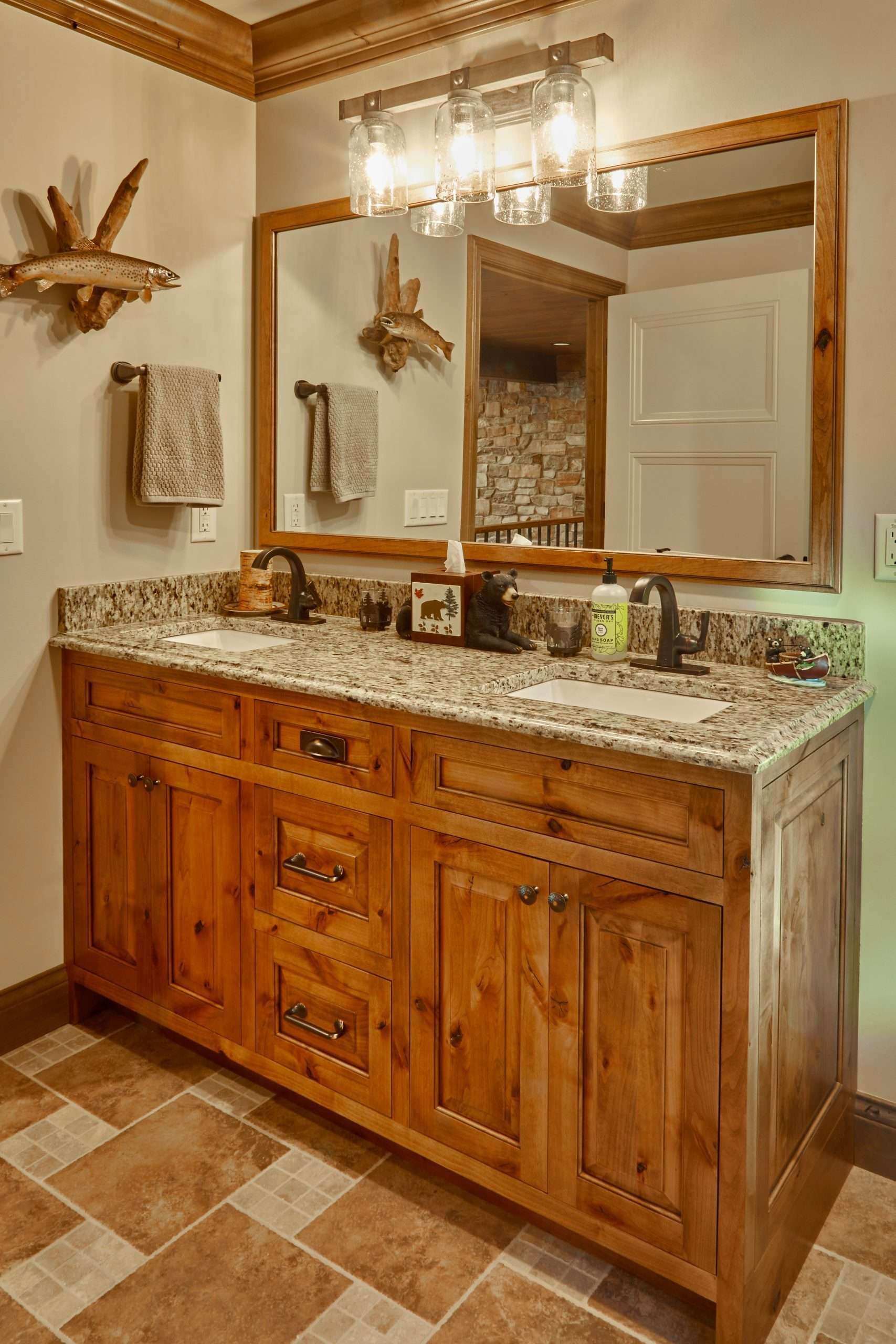 Rustic bathroom vanity with wood cabinet, granite countertop, mirror, and chandelier lighting