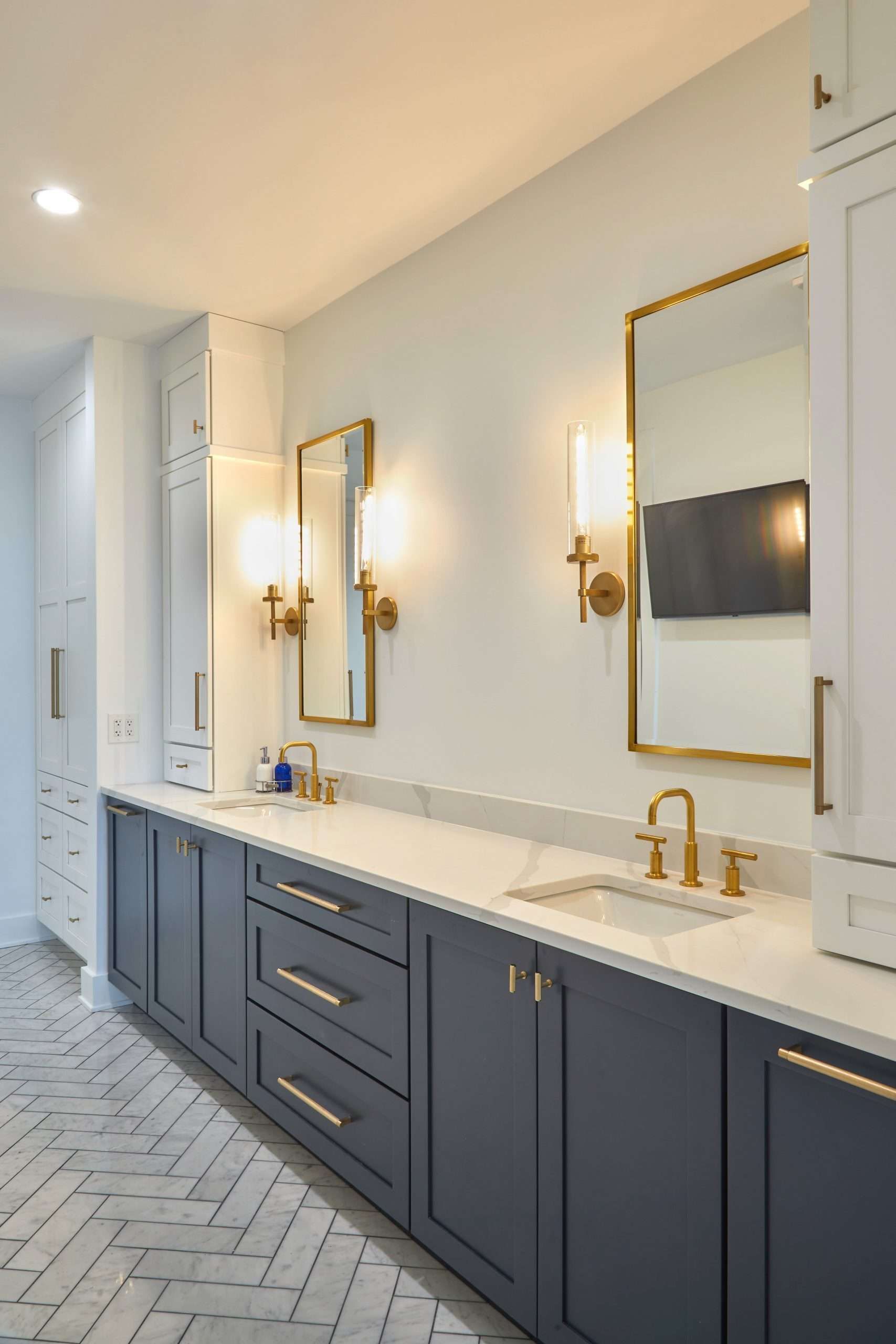 Modern bathroom vanity with dark cabinets, gold sconces, and a large mirror