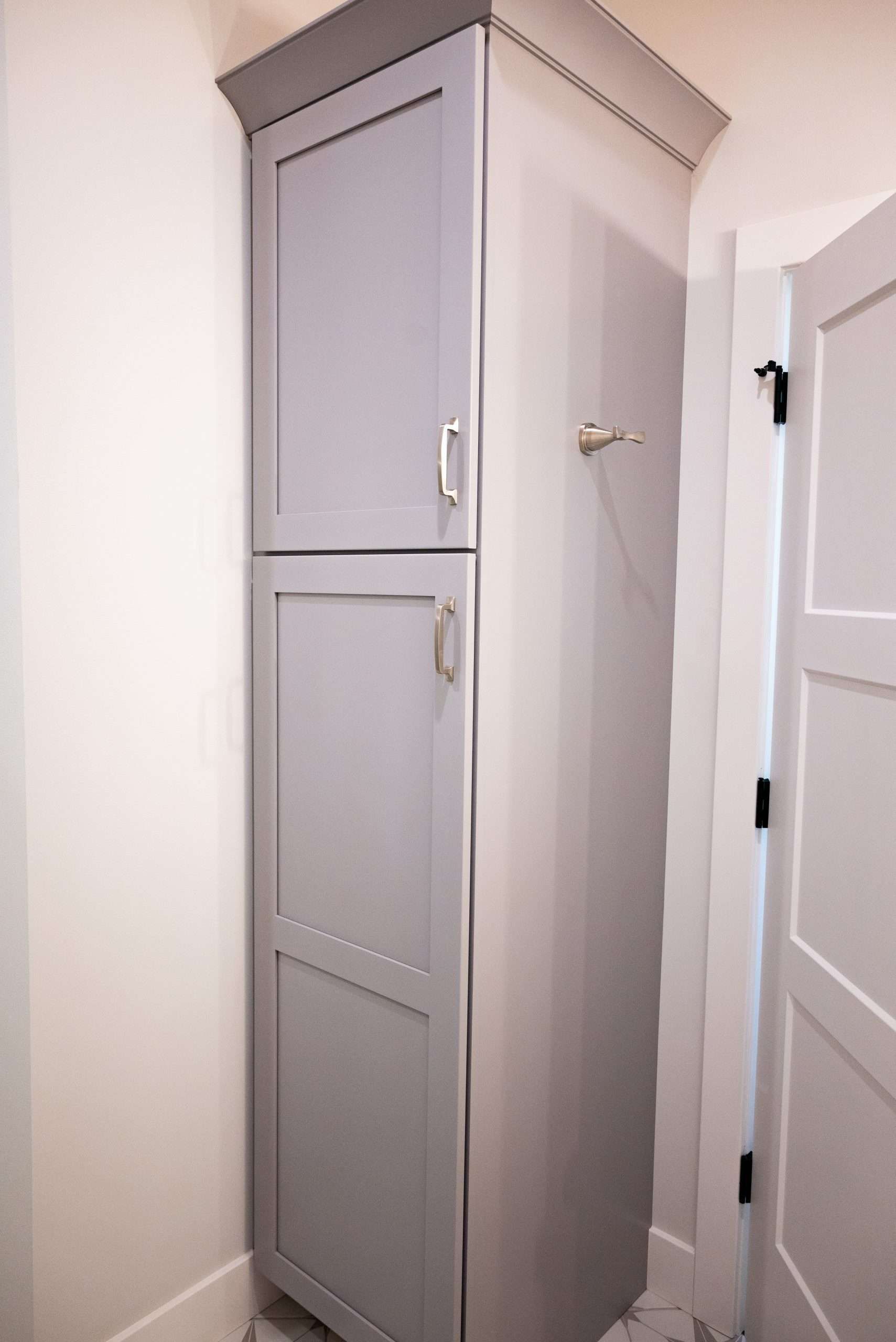 Tall gray cabinet in a white hallway beside a closed door.