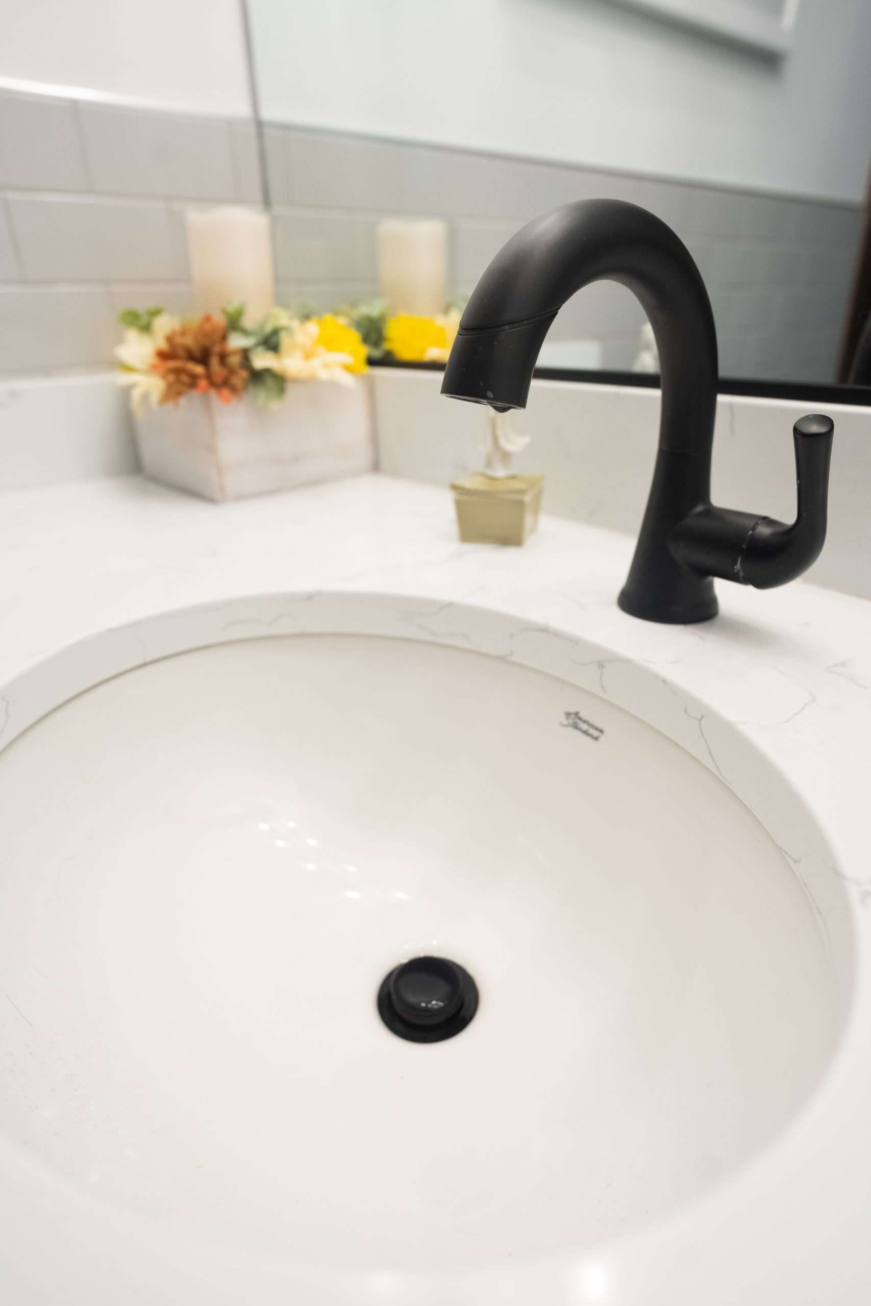 White bathroom sink with matte black faucet and small flowers on the counter