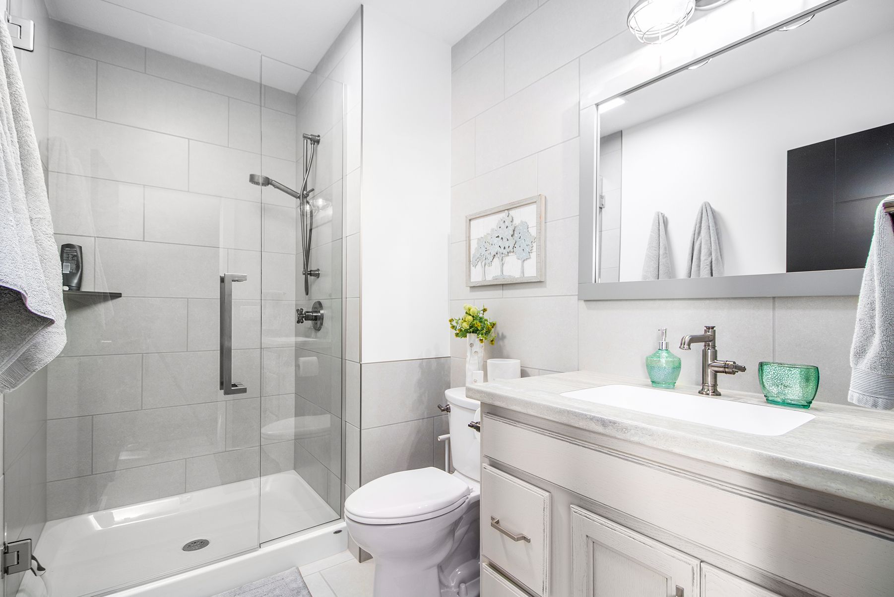 Bright modern bathroom with glass shower, white vanity, and toilet