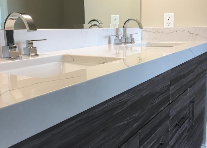 Modern bathroom vanity with double sinks, silver faucets, and dark wood cabinetry under a large mirror