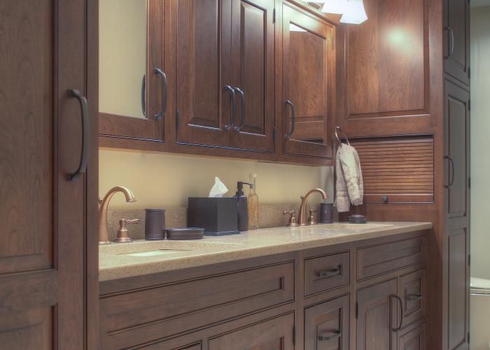 Wood-paneled kitchen with beige countertop, sink, and cabinets under warm lighting