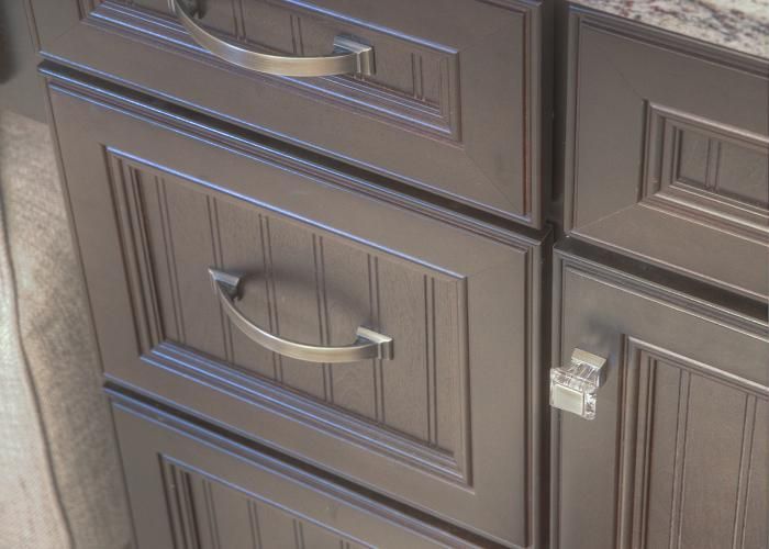 Close-up of dark wood cabinet drawers with silver handles and a small lock.