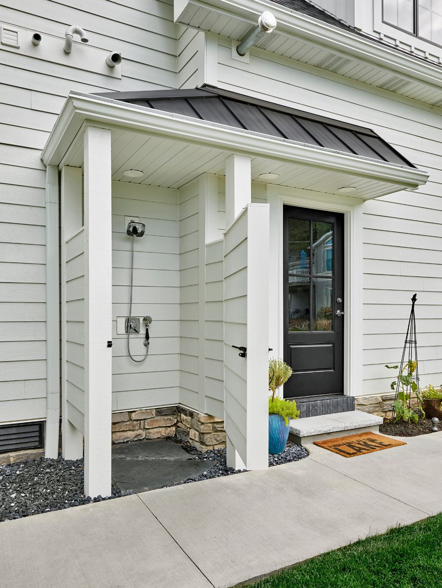 Front entrance of a white house with a dark door, covered porch, and concrete walkway.