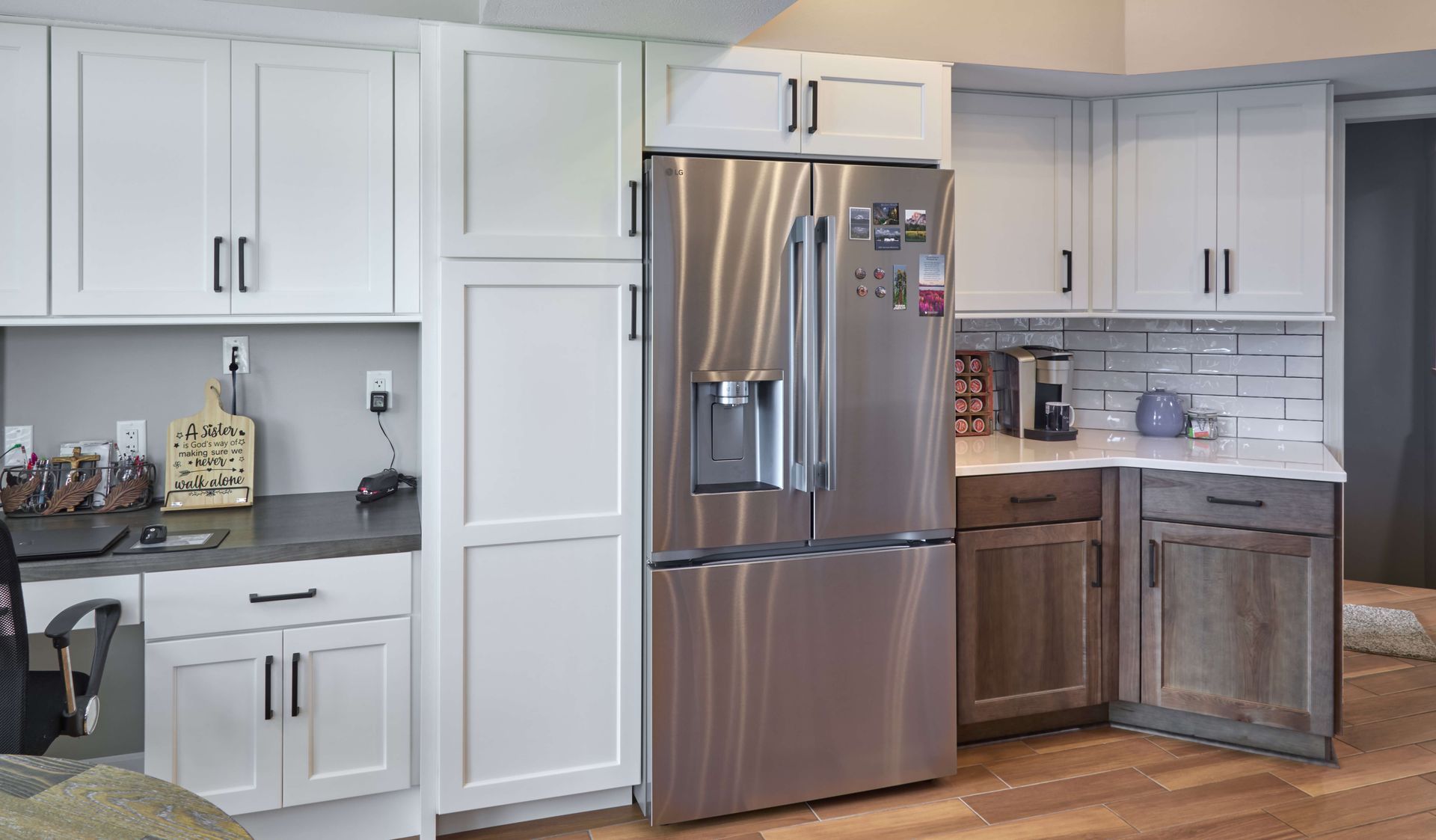 Bright modern kitchen with white cabinets, stainless steel fridge, and wood flooring