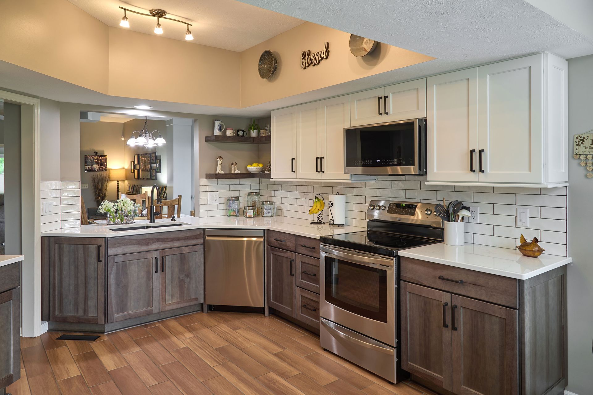 Modern kitchen with white cabinets, stainless steel appliances, and two-tone wood flooring