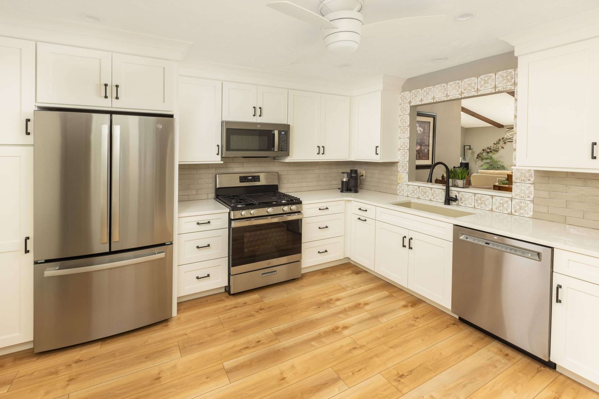 Bright white kitchen with stainless steel appliances, granite counters, and hardwood floors.