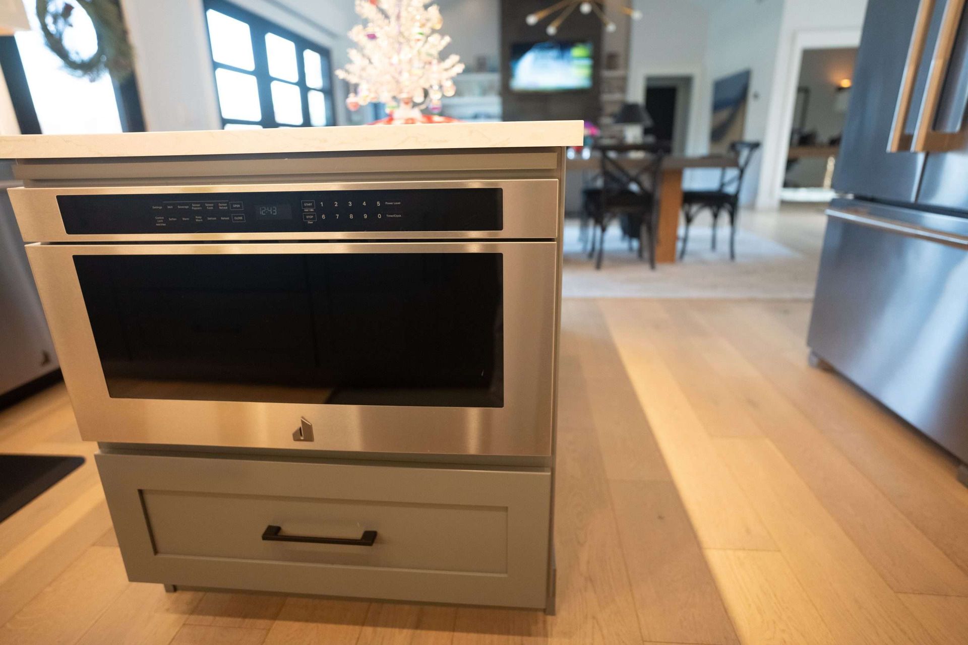 Built-in microwave drawer in a bright modern kitchen, with stainless steel appliances and wood floors.