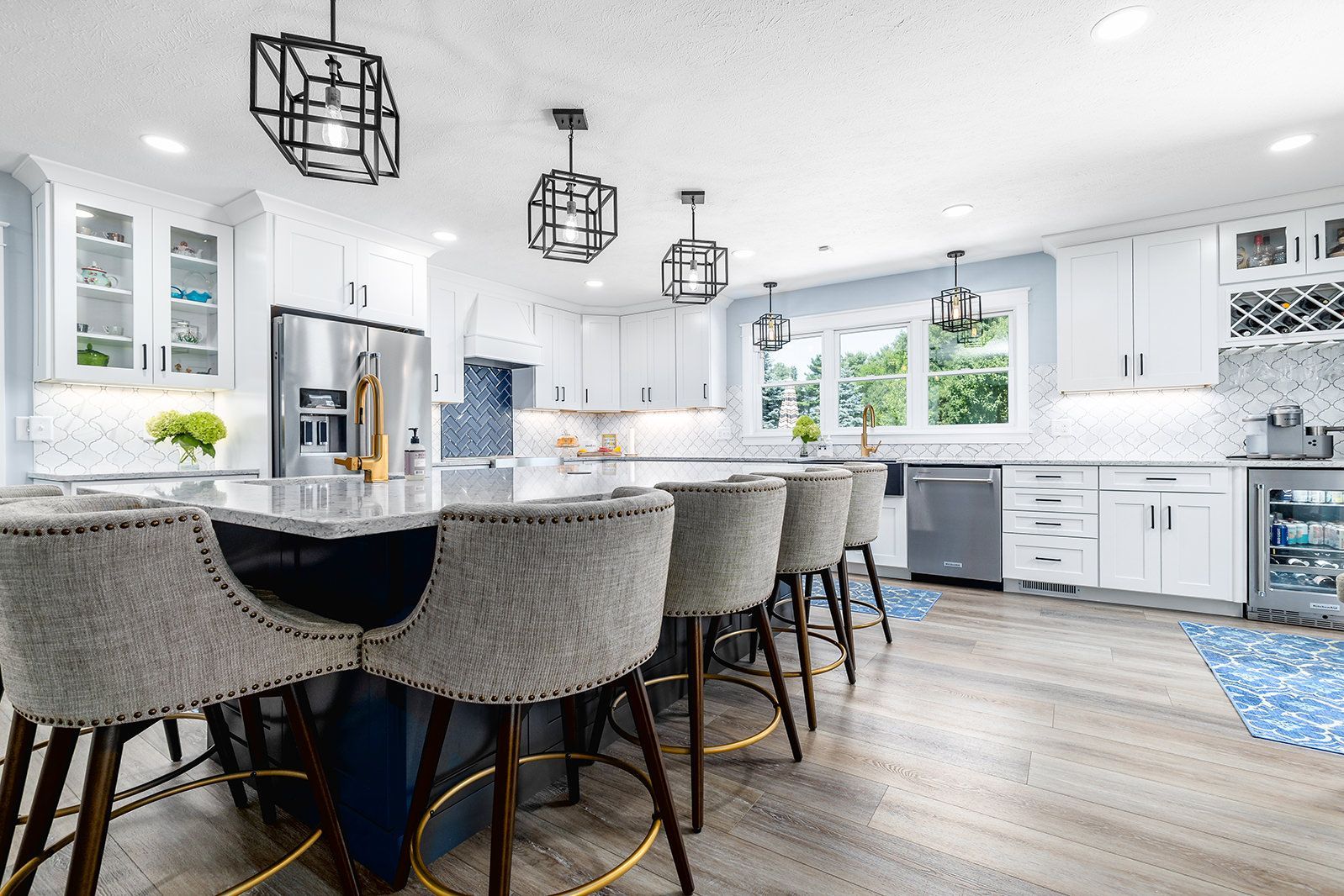 Bright modern kitchen with island seating, white cabinets, and large windows