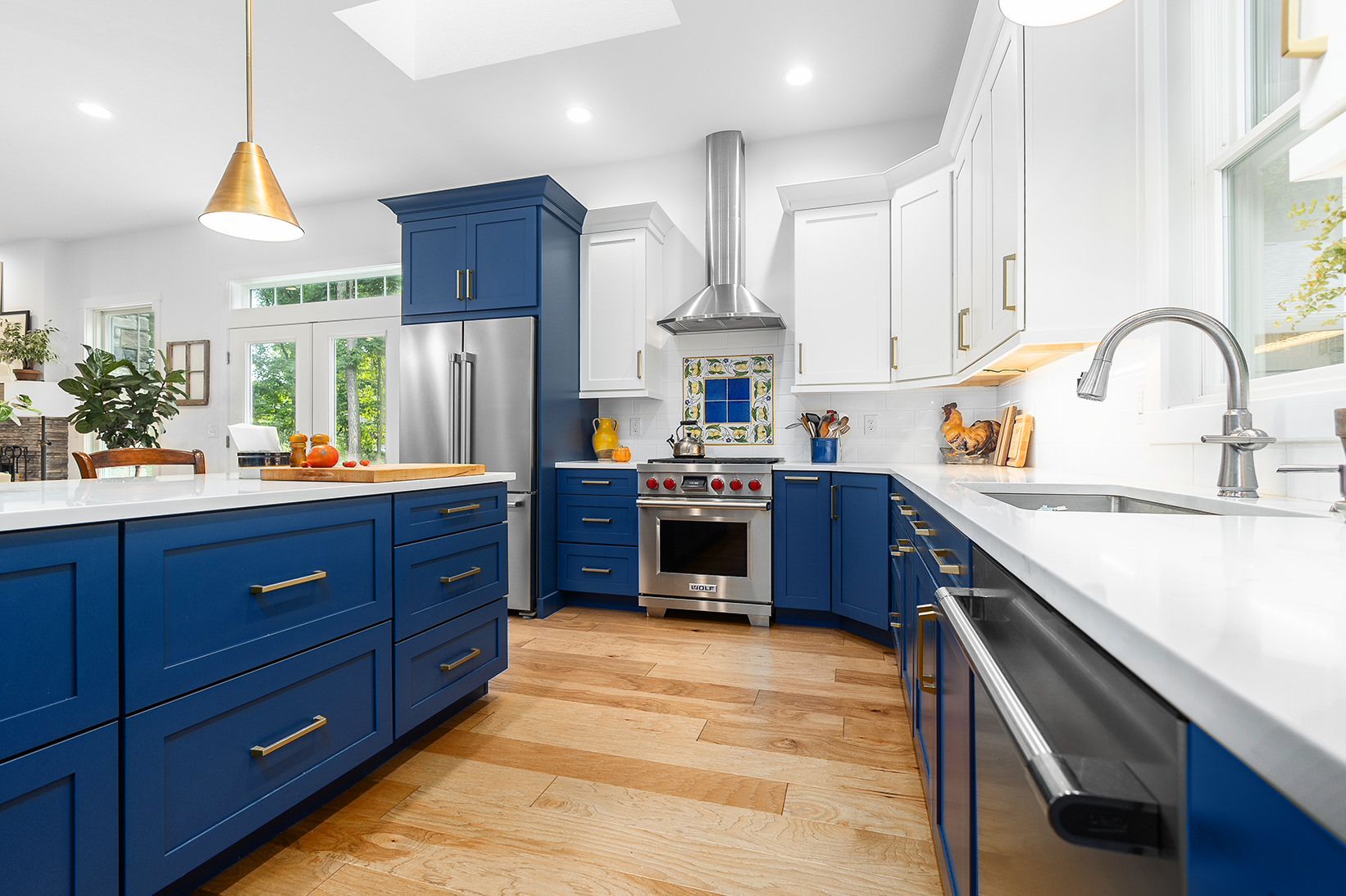 Bright kitchen with blue cabinets, white countertops, stainless range, and a large island.