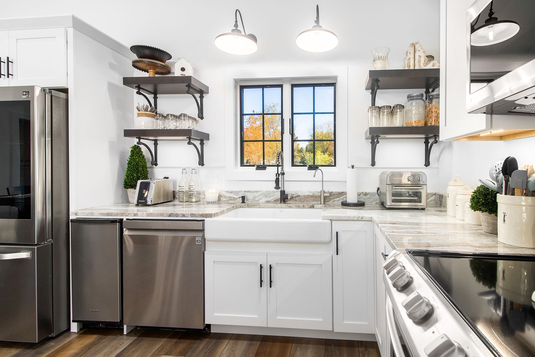 Bright modern white kitchen with stainless steel appliances, open shelves, and a farmhouse sink under two pendant lights