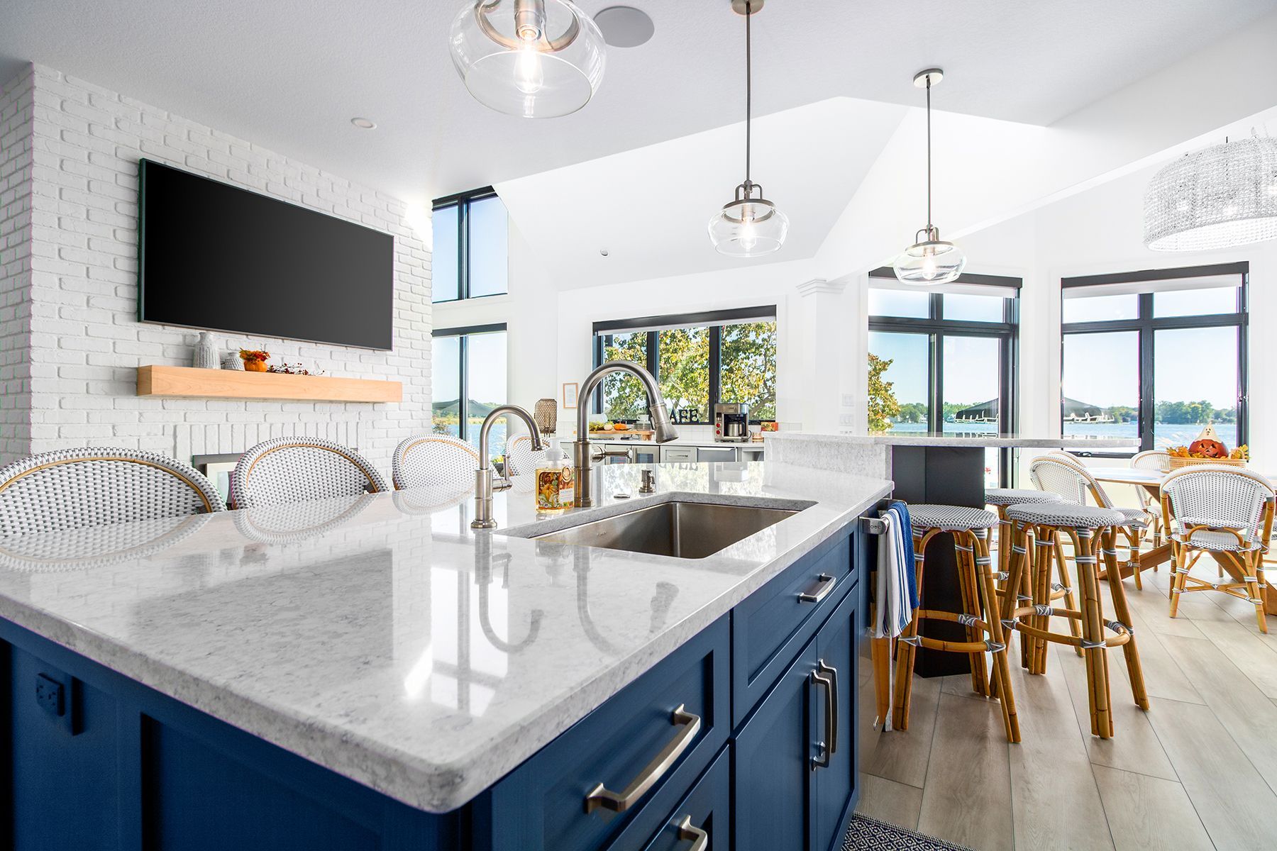 Bright modern kitchen with blue island cabinets, white countertops, and dining area by large windows